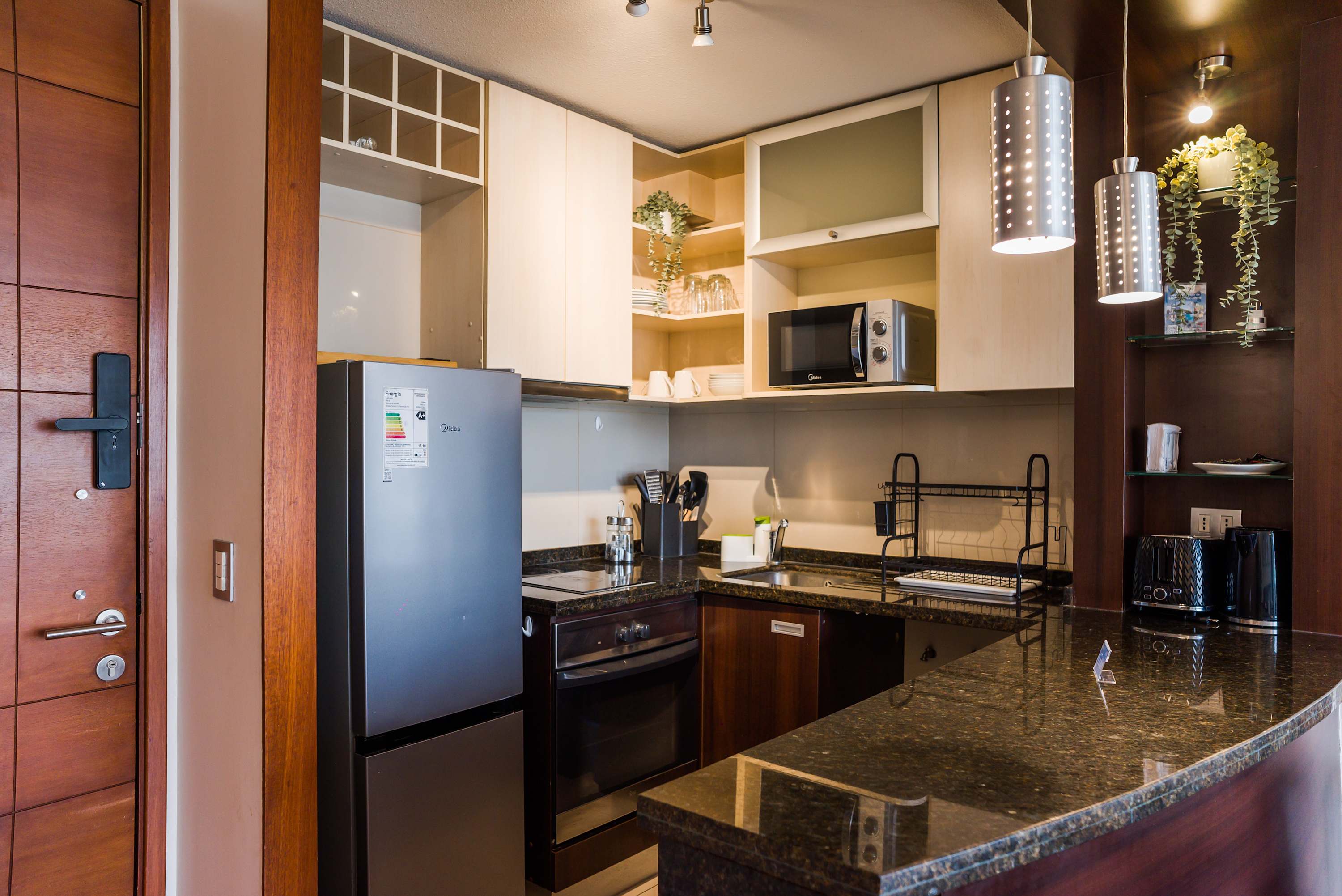 Private kitchen with sleek stainless-steel appliances, generous granite counters, and warm pendant lighting for convenient meals at home.