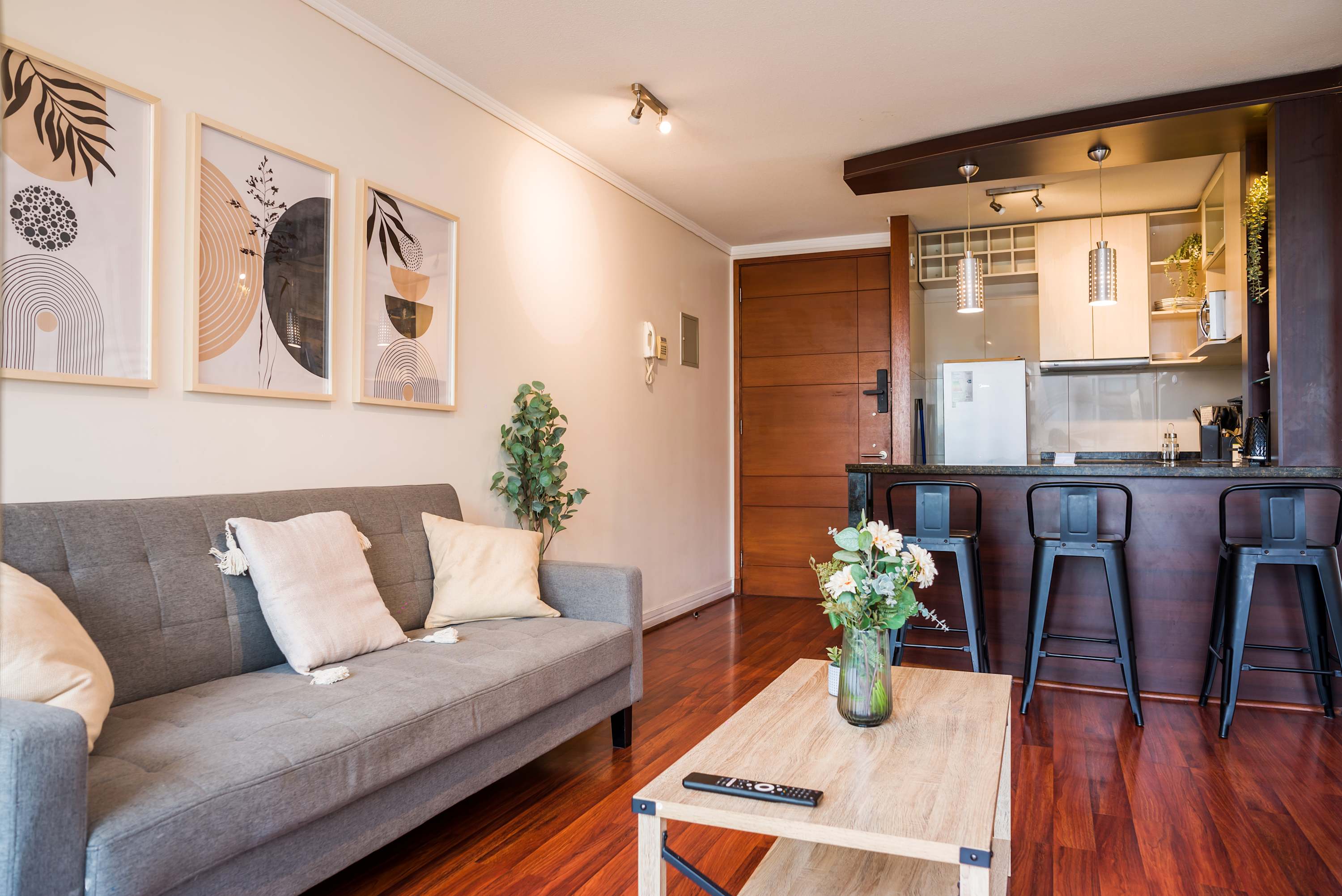 Private living area with a comfortable gray sofa, curated artwork, and a sleek kitchen island with three bar stools.