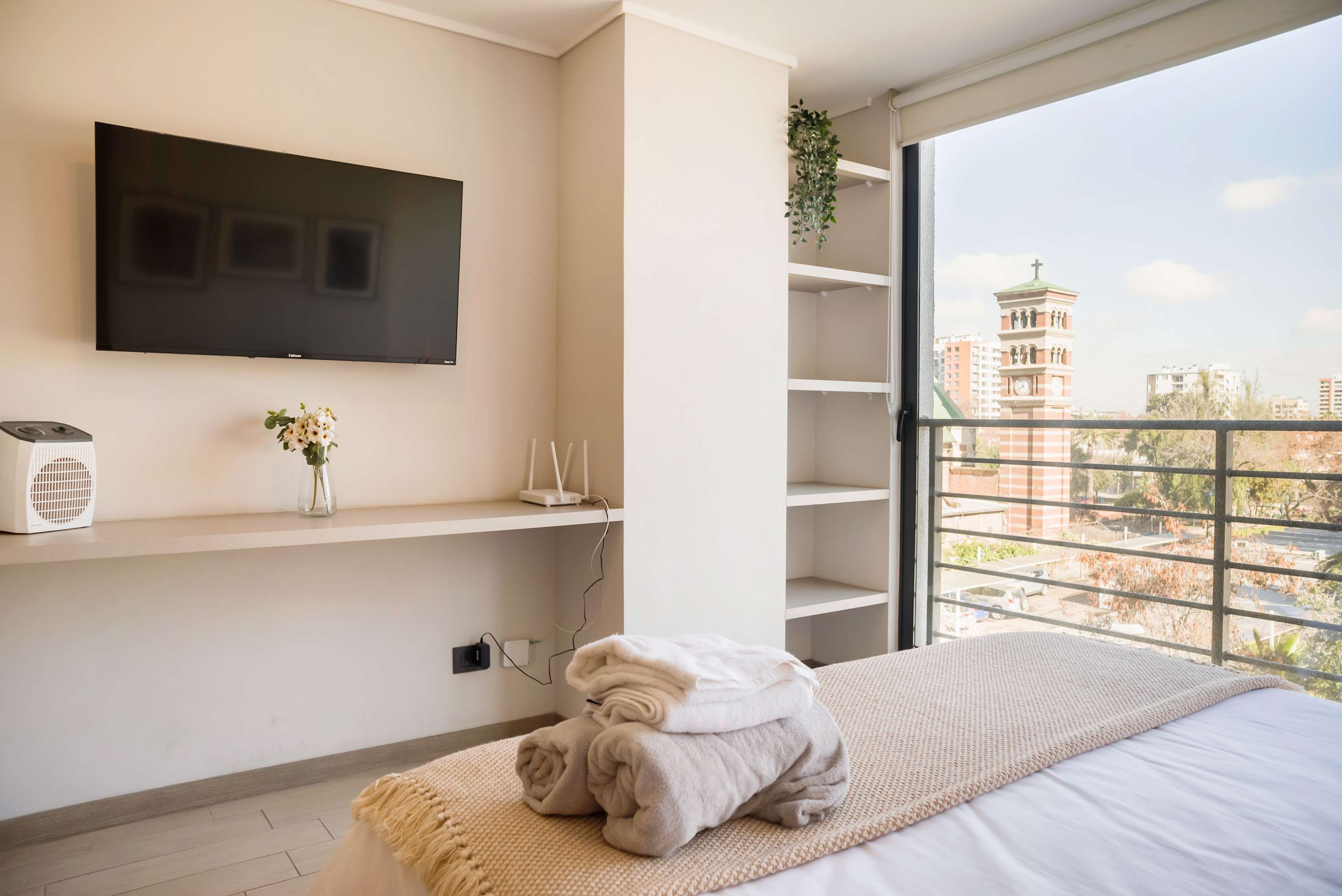 Enjoy stunning city views from this modern studio apartment, complete with a cozy bed and entertainment setup.