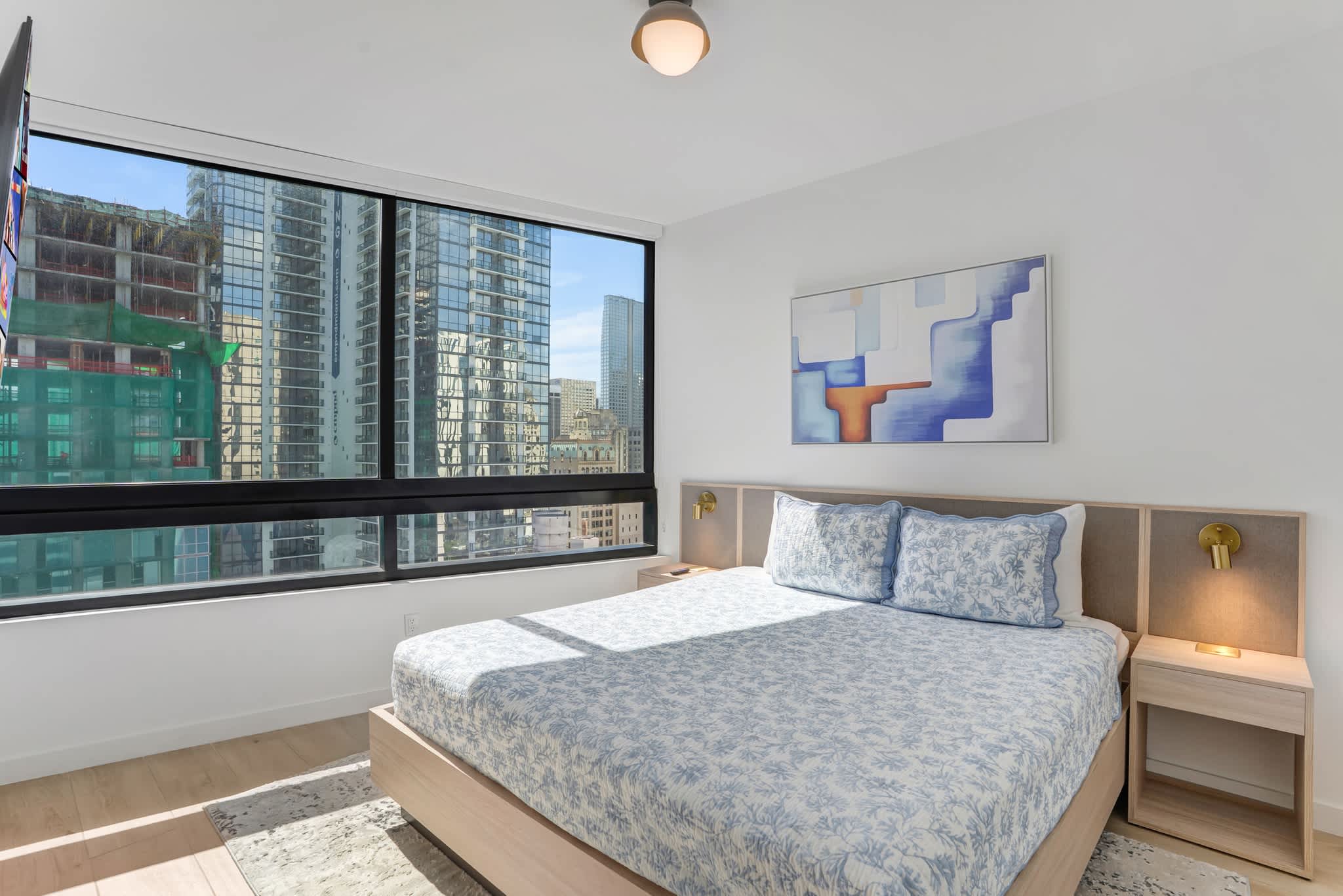 Relax in a modern bedroom with stunning city views and stylish decor, perfect for a restful stay.