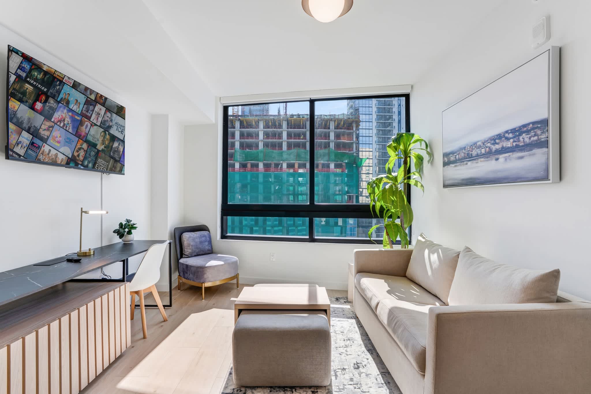 Modern studio living area with natural light, cozy seating, and a workspace, perfect for relaxation or remote work.