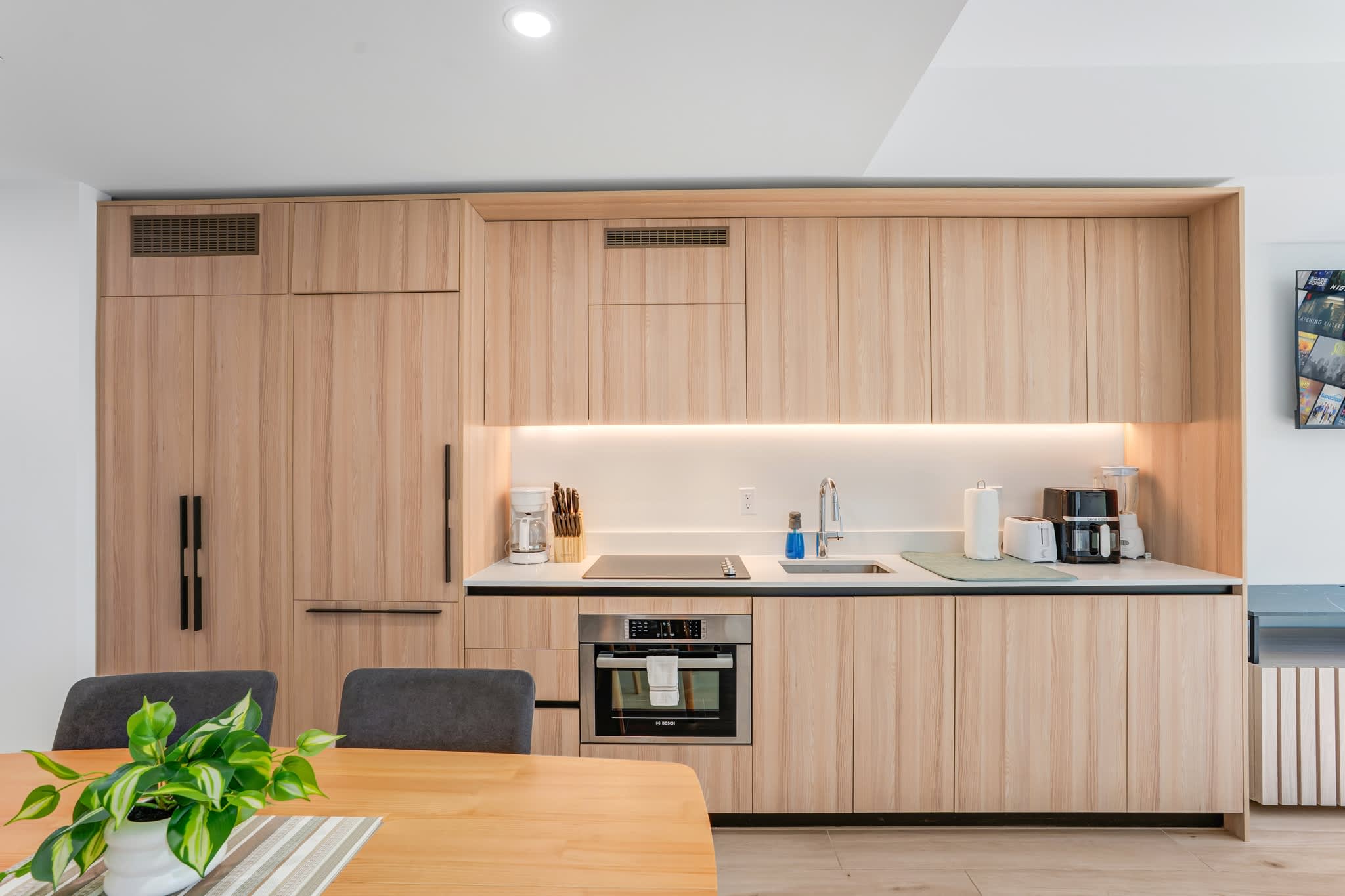 Sleek and modern kitchen with integrated appliances and stylish wood finishes, perfect for cooking and dining in comfort.
