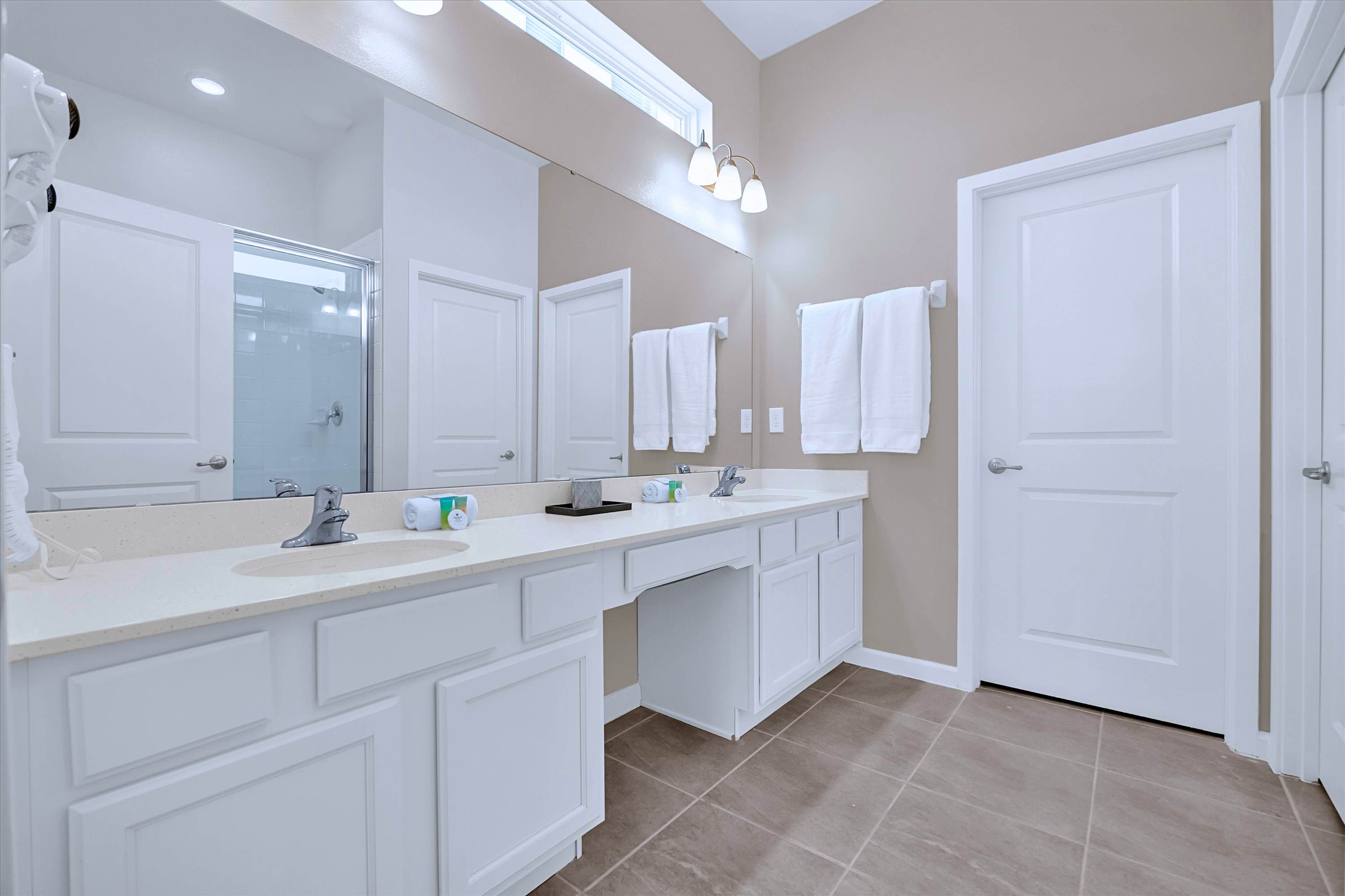 En-suite bathroom featuring a double vanity, dual sinks, and large vanity mirror