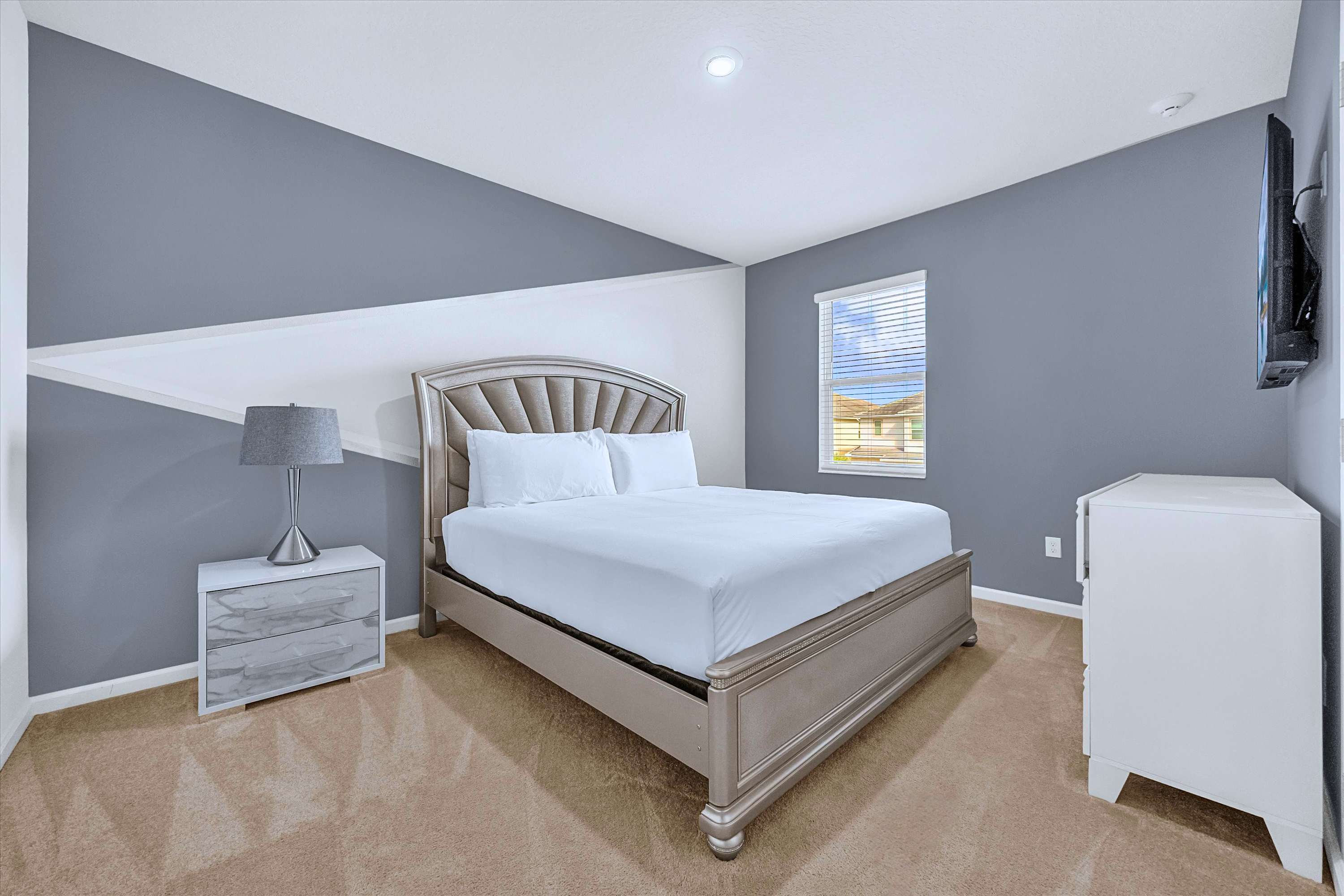King Bed with premium linens, bedside lamp, smart TV, and media cabinet storage