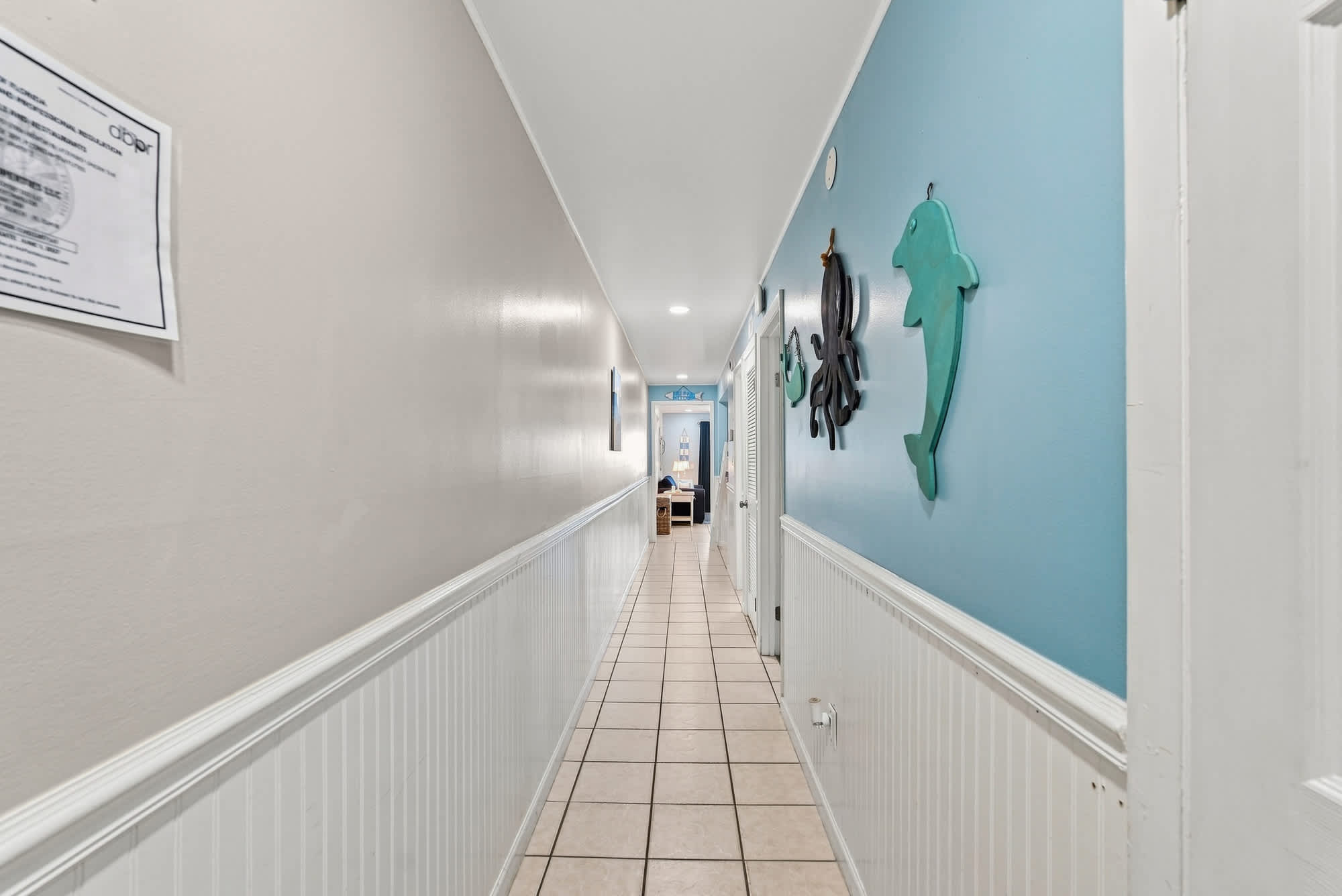 The Summit 308  – Long hallway with blue walls, decorative sea animal art, and tiled floor leading to a living area.