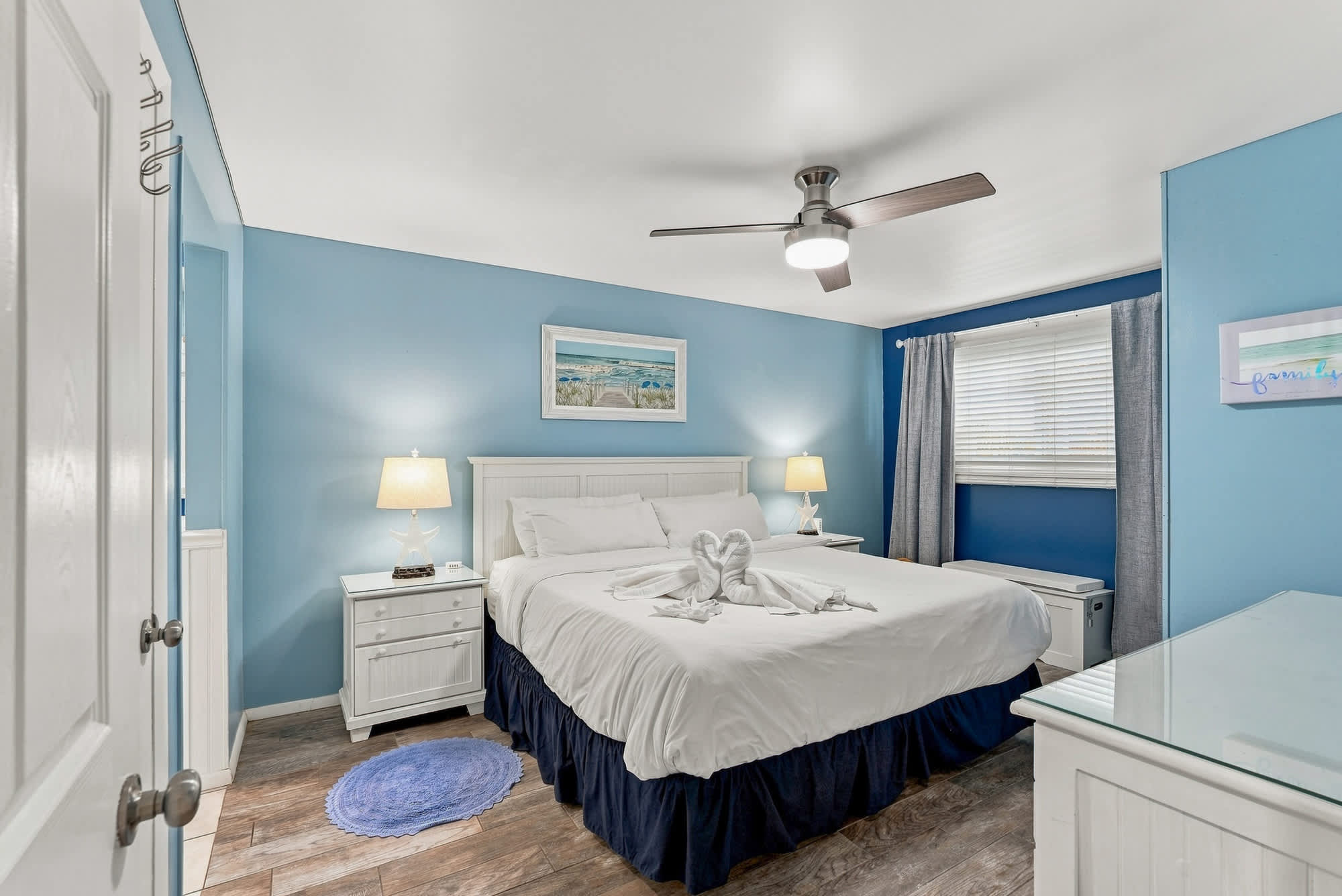 The Summit 308  – Bedroom with a queen bed, blue walls, two lamps, and a window with curtains.