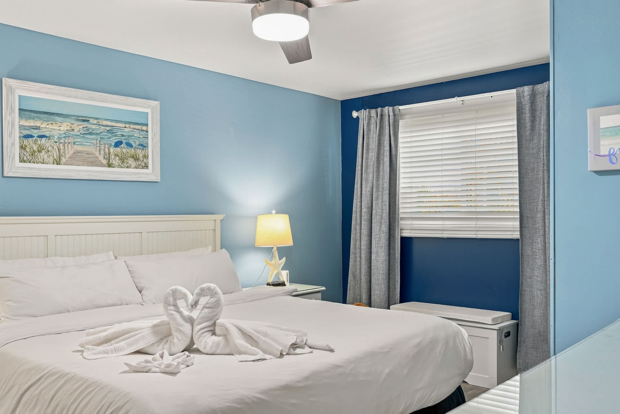 The Summit 308  – Cozy bedroom with double bed, blue walls, decorative artwork, and window with gray curtains.