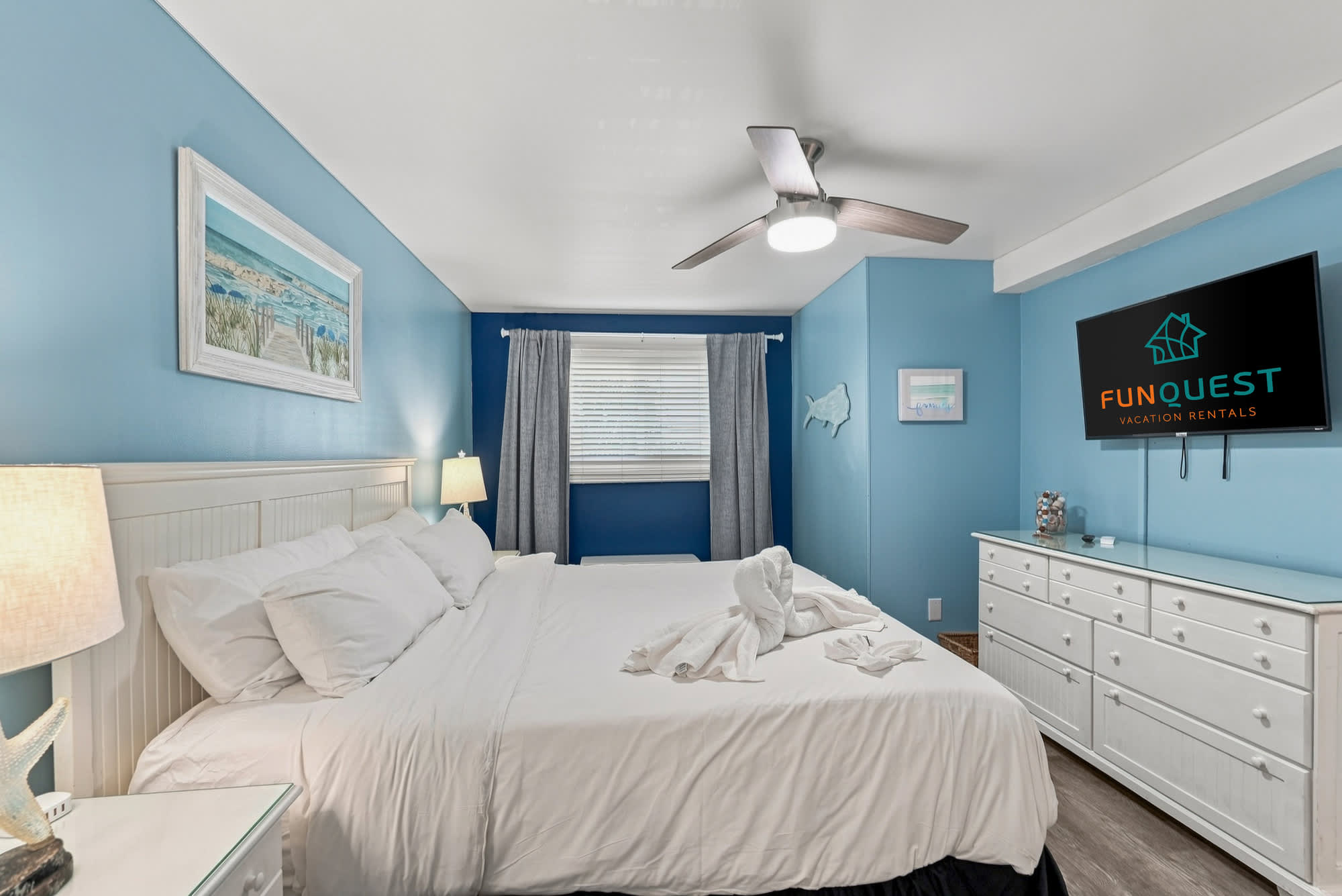 The Summit 308  – Blue-themed bedroom with a queen bed, TV, dresser, and a window with blinds.