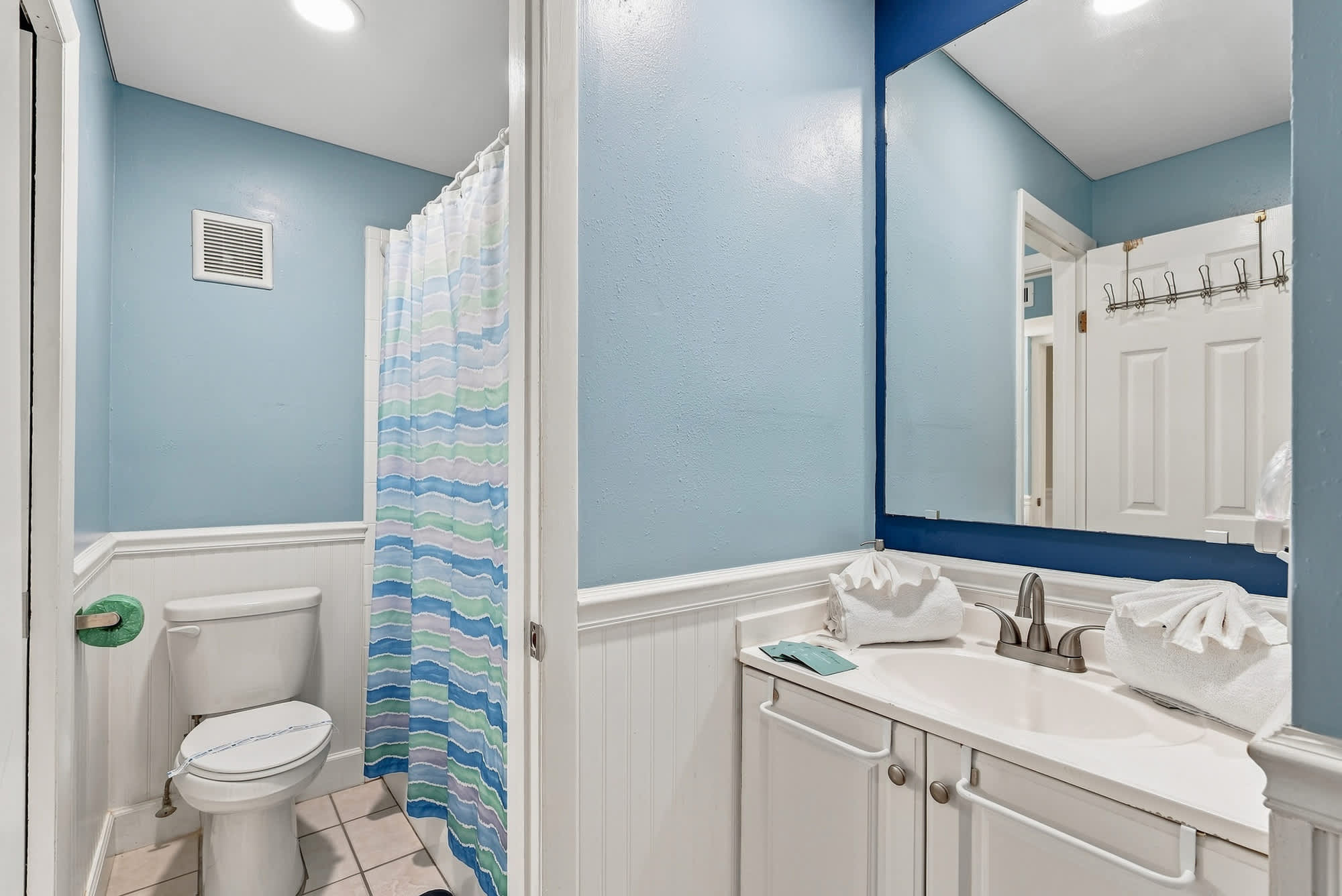 The Summit 308  – Bathroom featuring a blue wall, shower curtain, sink with towels, and toilet.