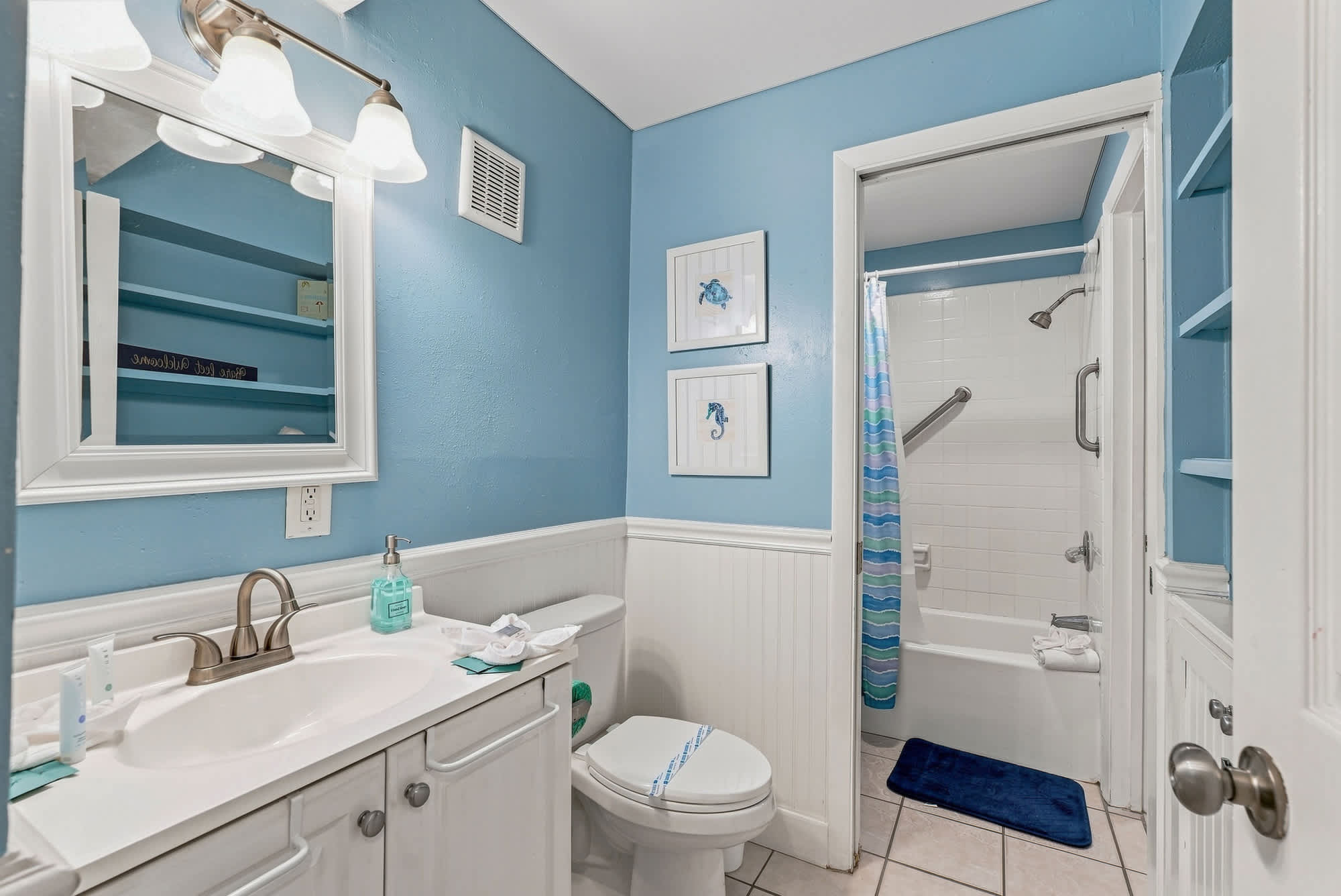 The Summit 308  – Bright blue bathroom with a vanity, mirror, shower, and decorative wall art.