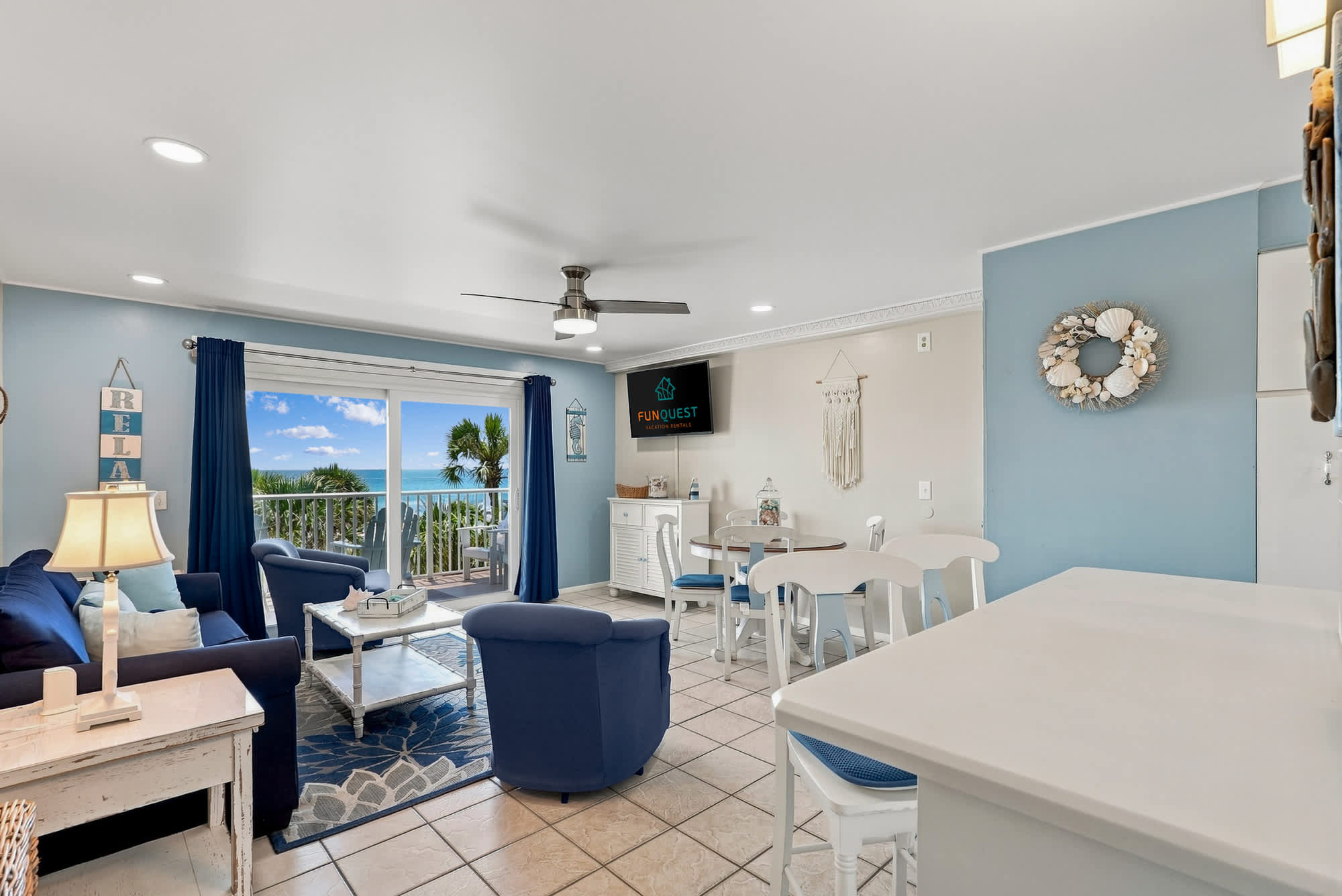 The Summit 308  – Living room with blue furnishings, dining area, and ocean view through sliding glass doors.