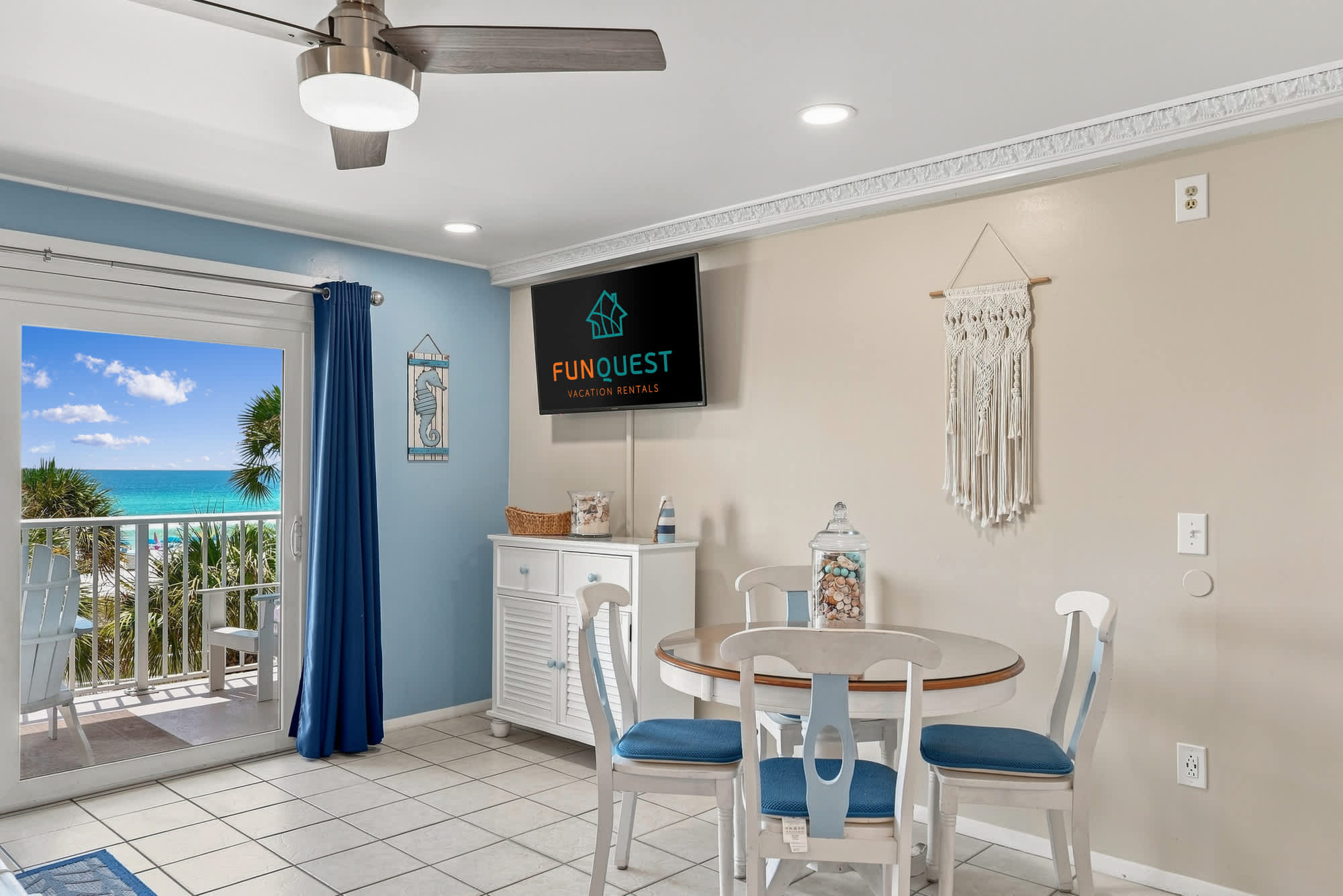 The Summit 308  – Bright dining area with a circular table, blue accents, a TV, and balcony view of the ocean.