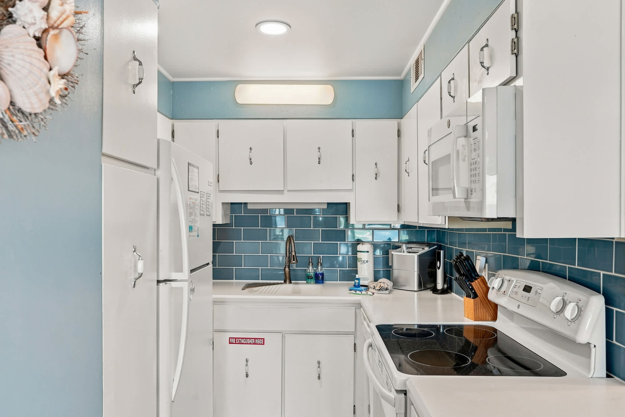 The Summit 308  – Compact kitchen with white cabinets, blue tiled backsplash, and modern appliances.