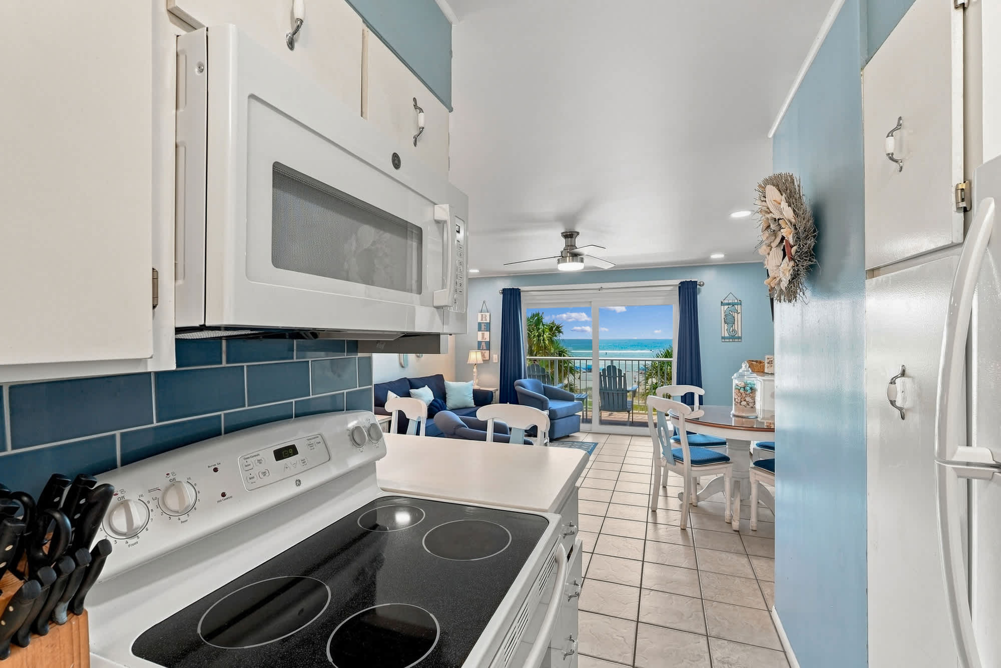 The Summit 308  – Kitchen and dining area with ocean view through sliding glass doors. Blue walls, white furniture.