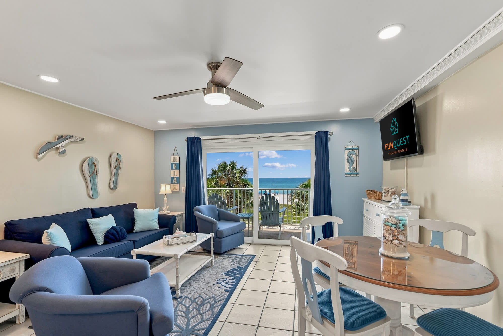 The Summit 308  – Living room with blue seating, dining table, and ocean view through sliding glass doors.