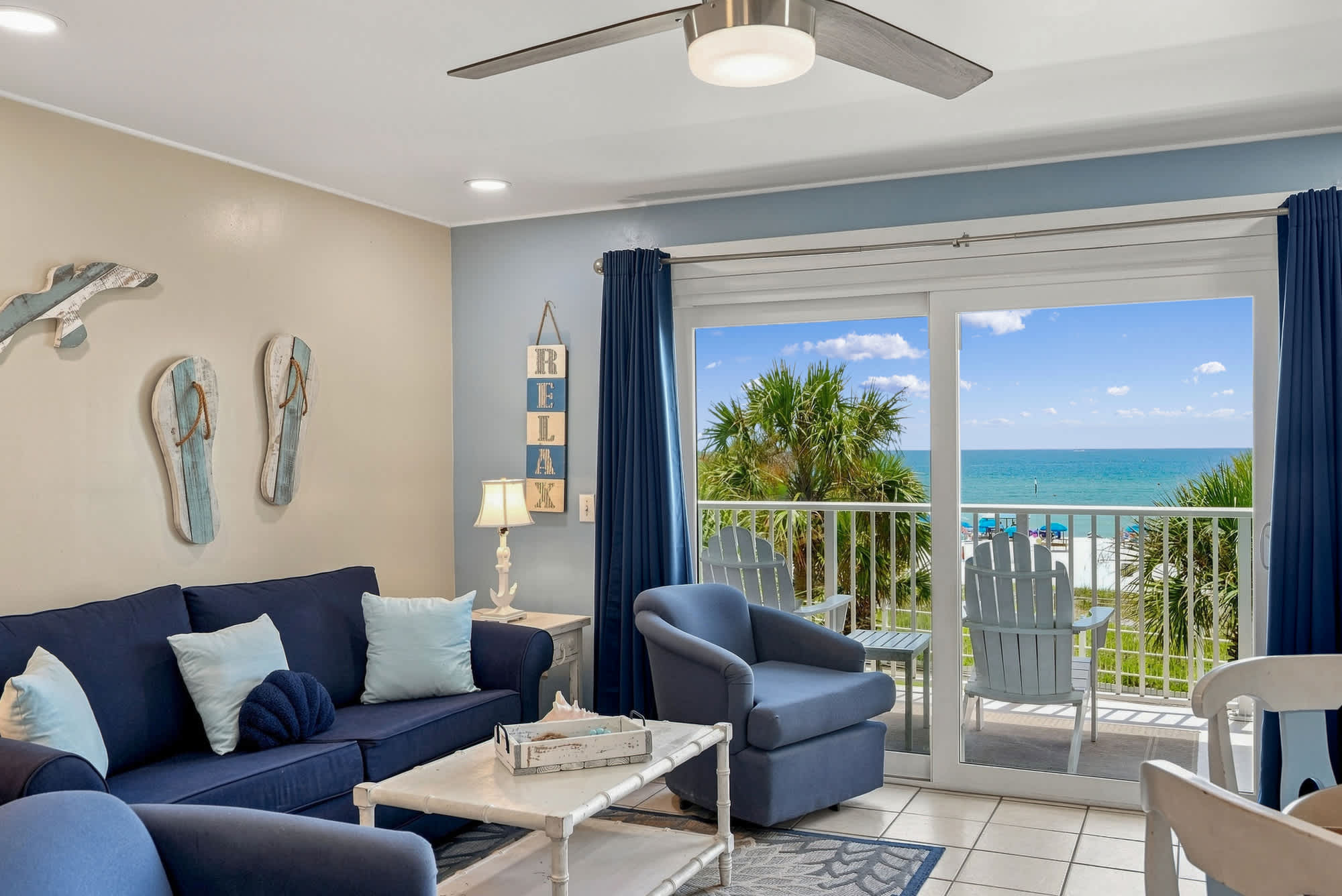 The Summit 308  – Living room with blue sofas, coffee table, and beachfront view through sliding glass doors.