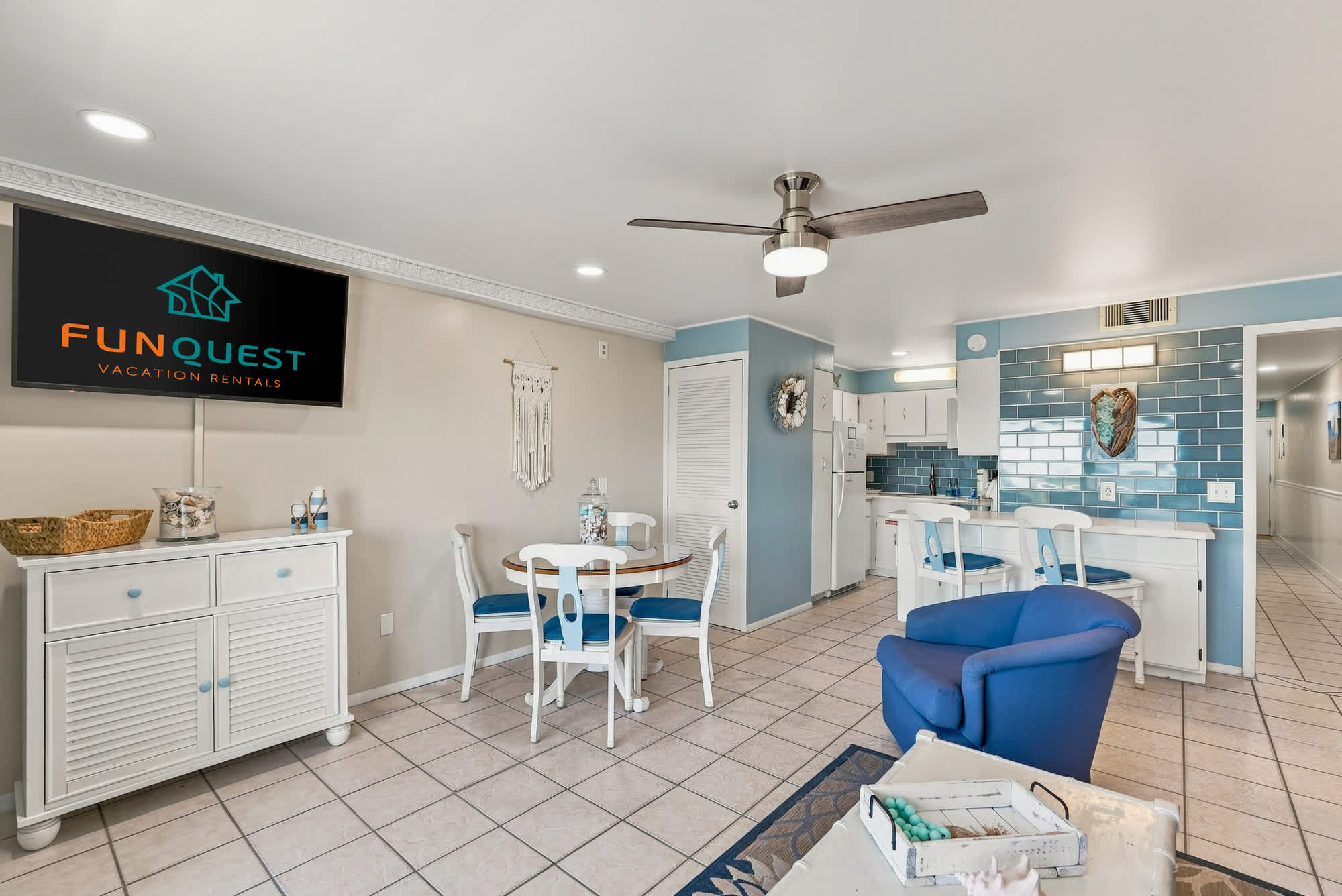 The Summit 308  – Cozy living area with dining table, kitchen, blue accent chair, and decorative coastal decor.
