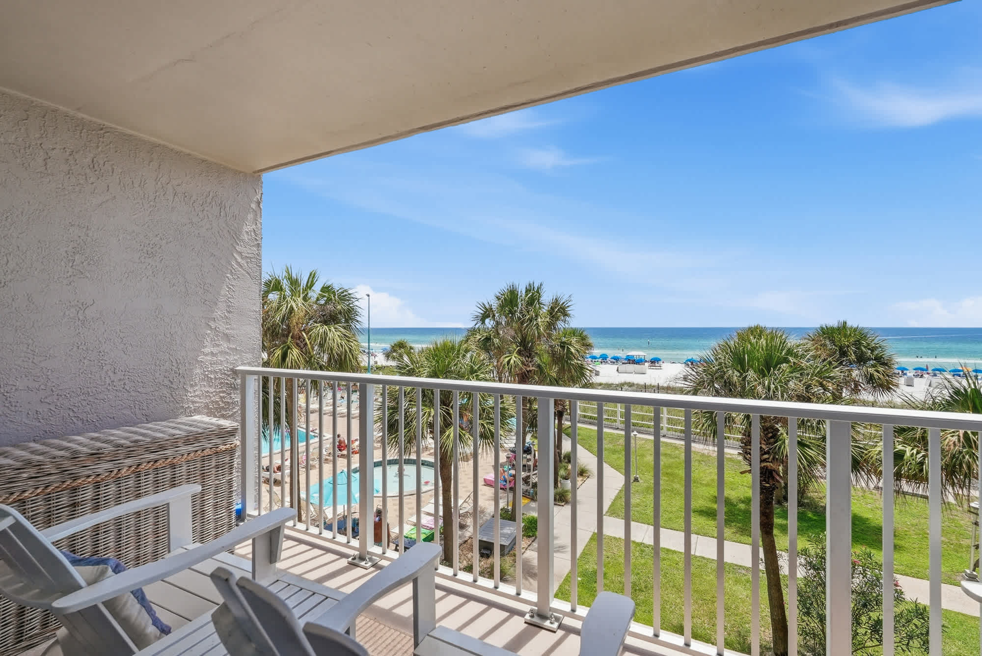 The Summit 308  – Balcony view of ocean, palm trees, and pool area from a vacation rental.