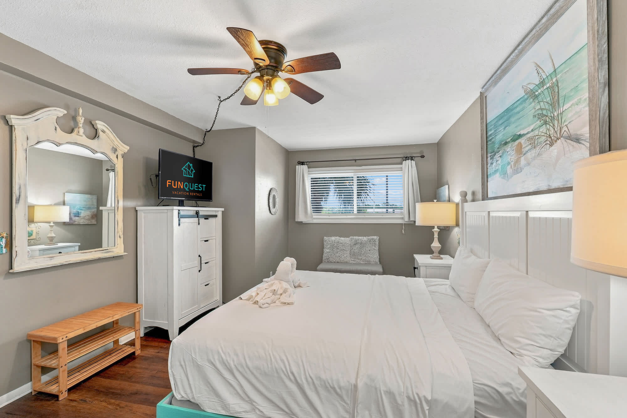 The Summit 225 – Cozy bedroom with a queen bed, dresser, TV, and large window with light curtains.
