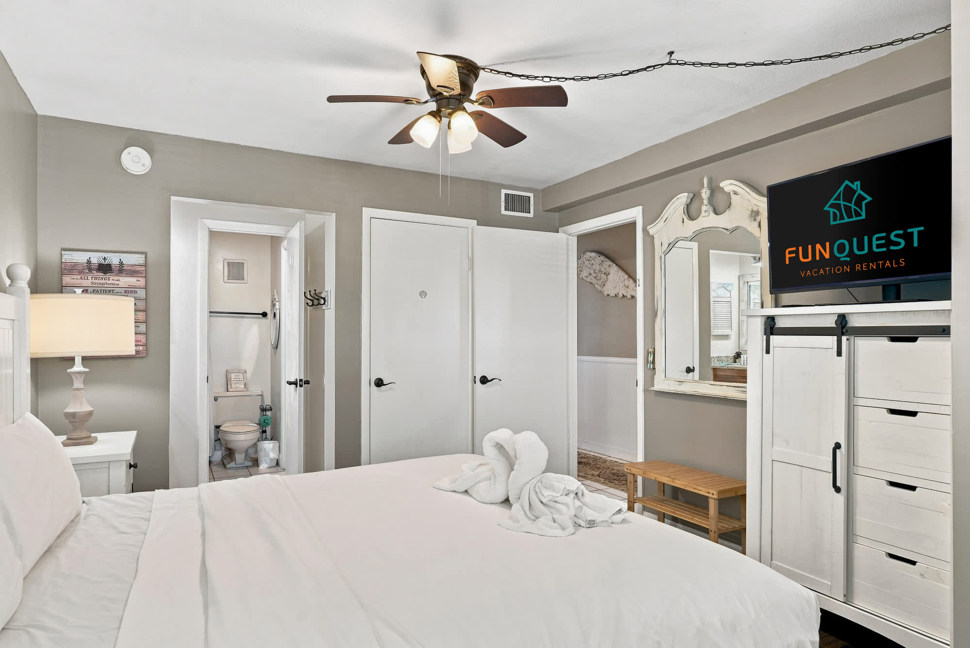 The Summit 225 – Cozy bedroom with a ceiling fan, television, en-suite bathroom, and decorative towel swans on the bed.