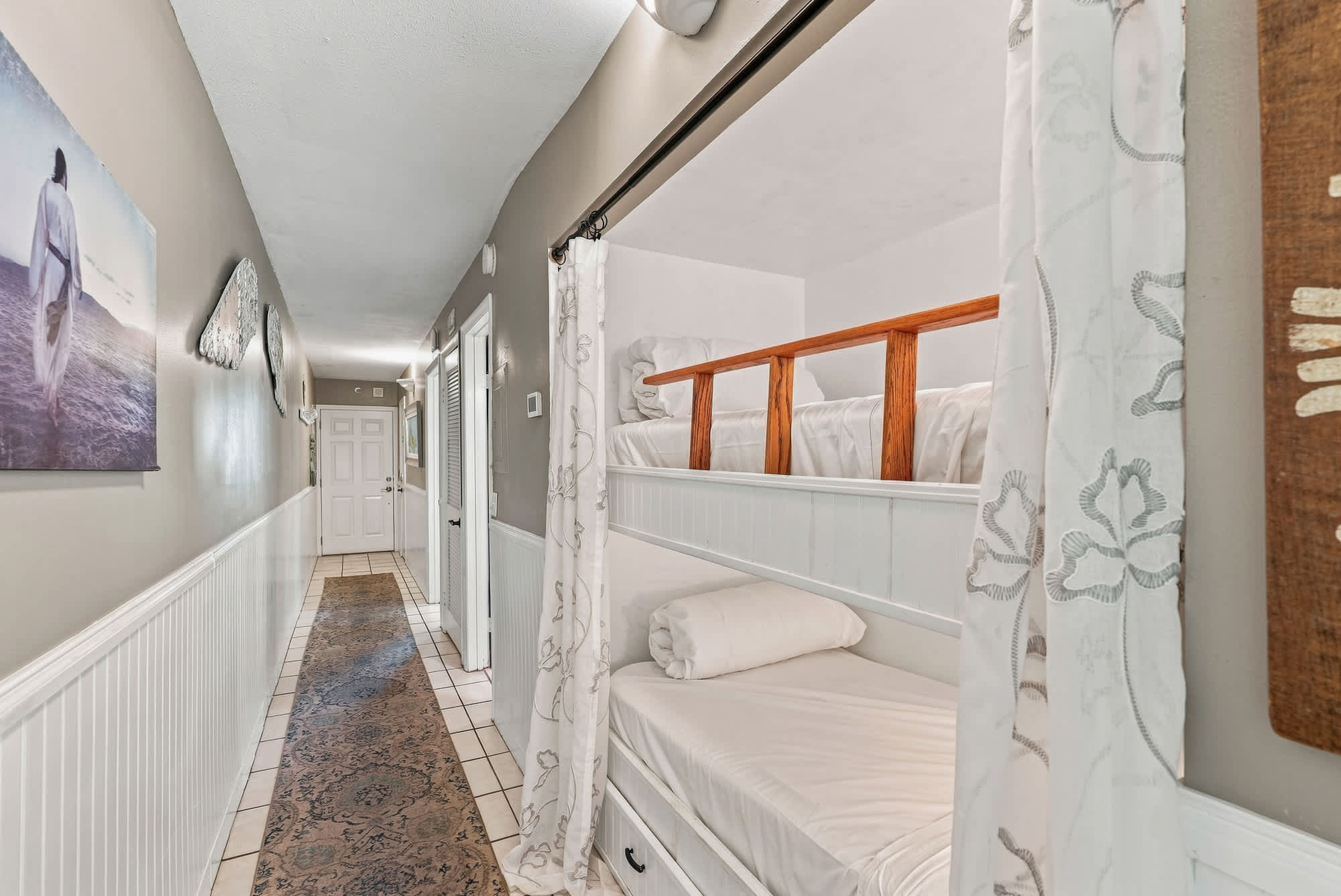 The Summit 225 – Hallway with bunk beds, light-colored walls, decorative artwork, and tiled flooring.