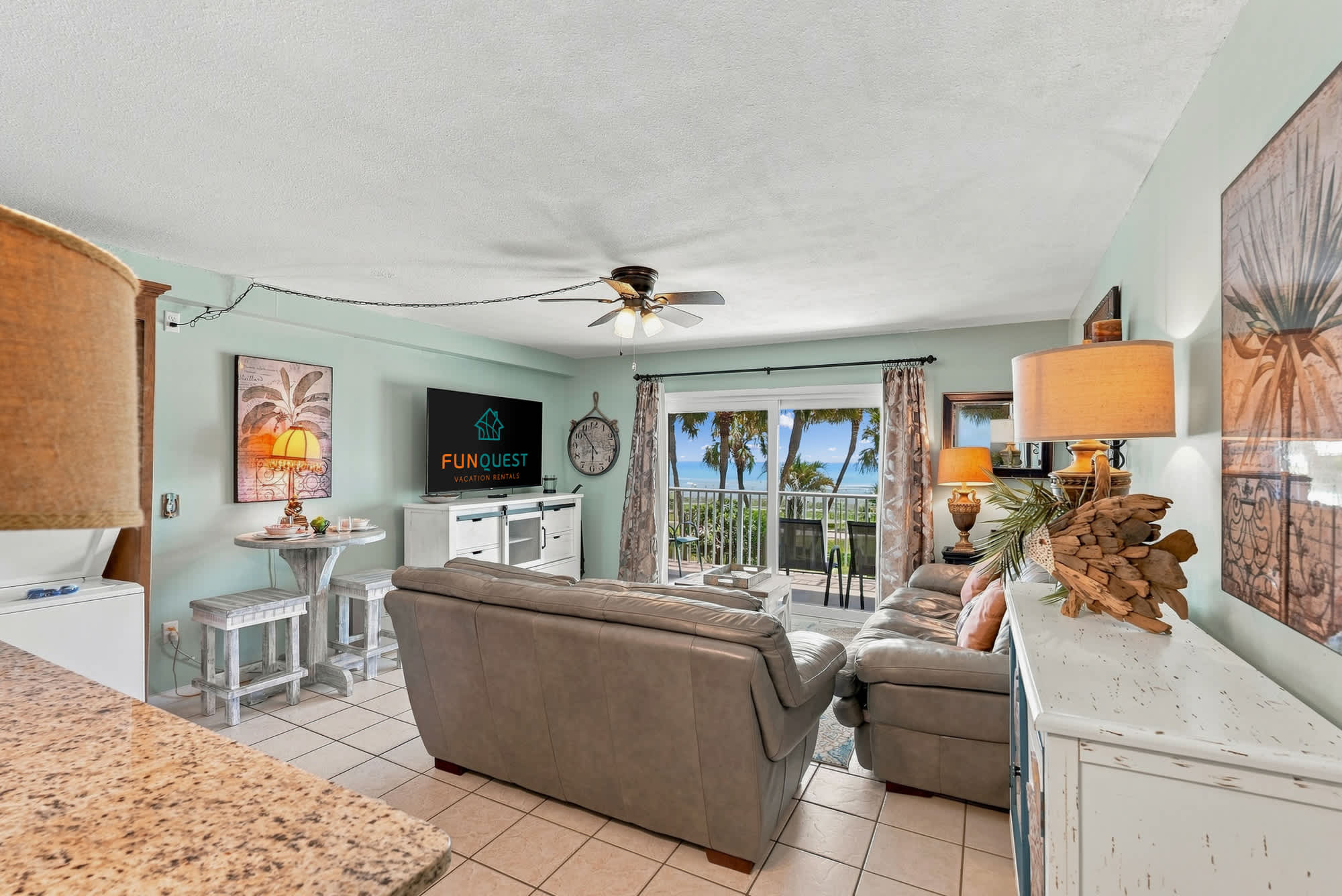 The Summit 225 – Living room with a grey sofa, flat-screen TV, table, and balcony offering ocean views.