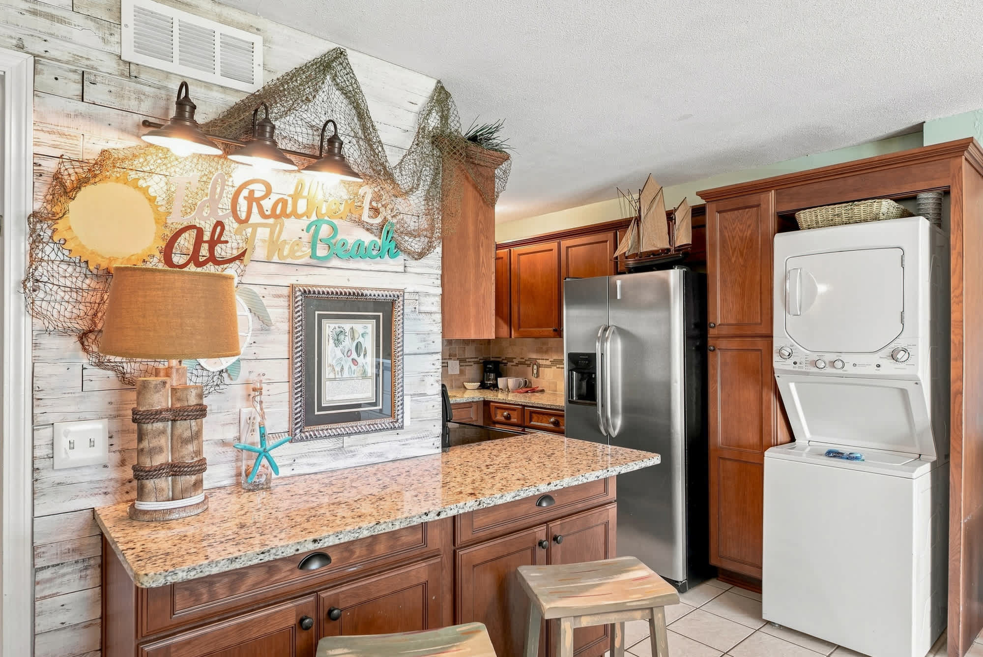 The Summit 225 – Kitchen area with granite countertop, wooden cabinets, and laundry appliances in a bright space.