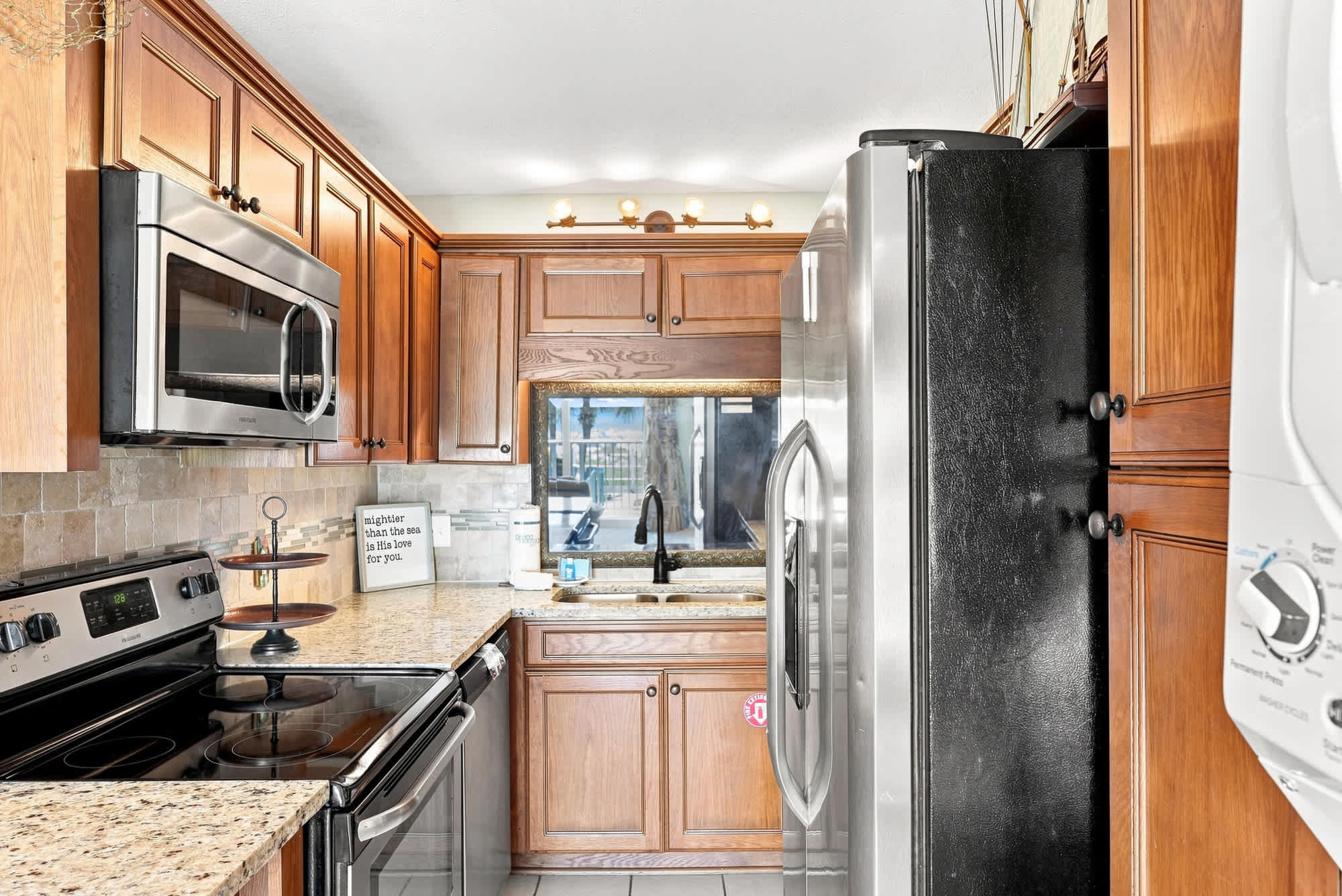 The Summit 225 – Modern kitchen with wooden cabinets, granite countertops, stainless steel appliances, and a window view.