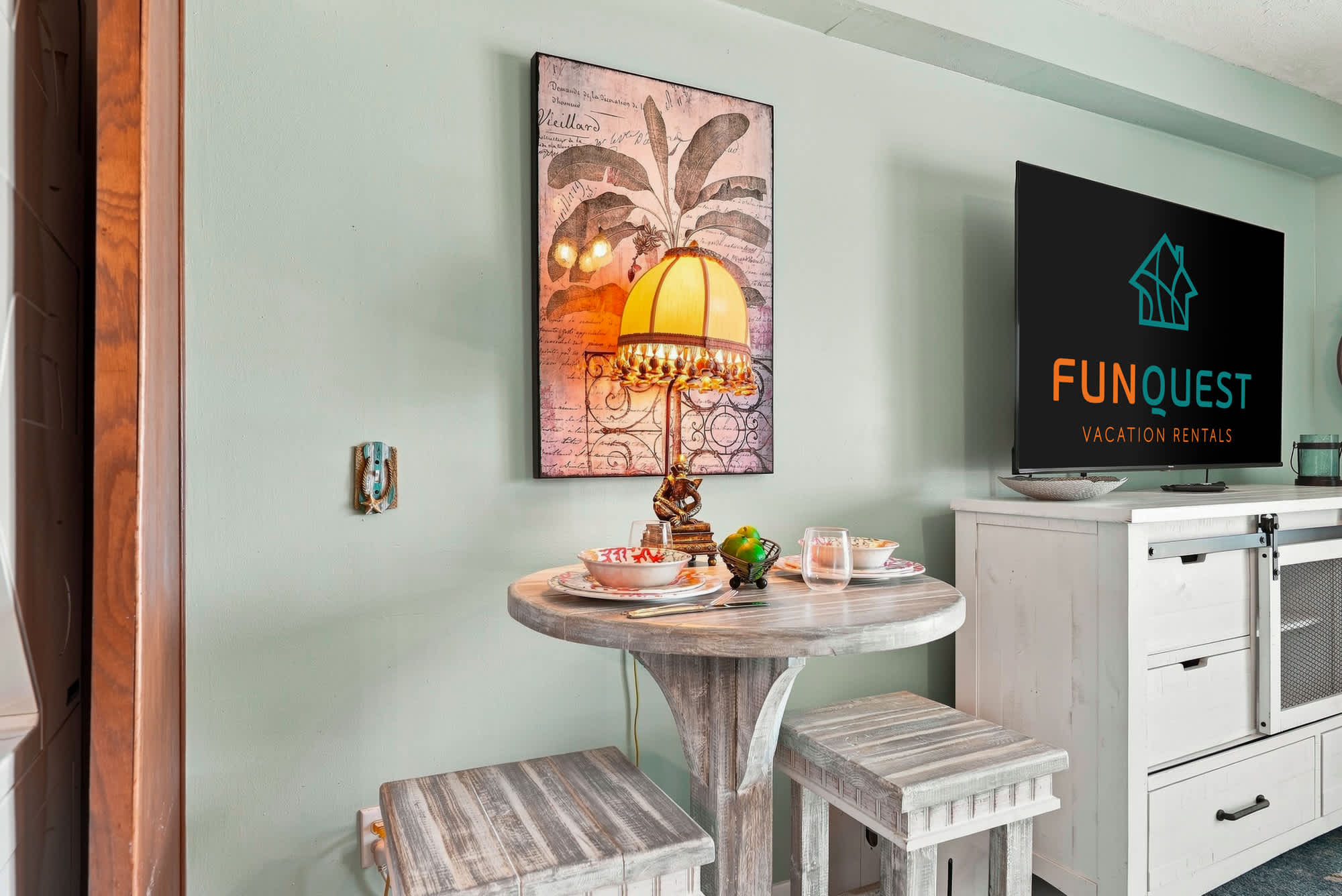 The Summit 225 – Cozy dining area with a round table, two stools, and a wall-mounted TV.