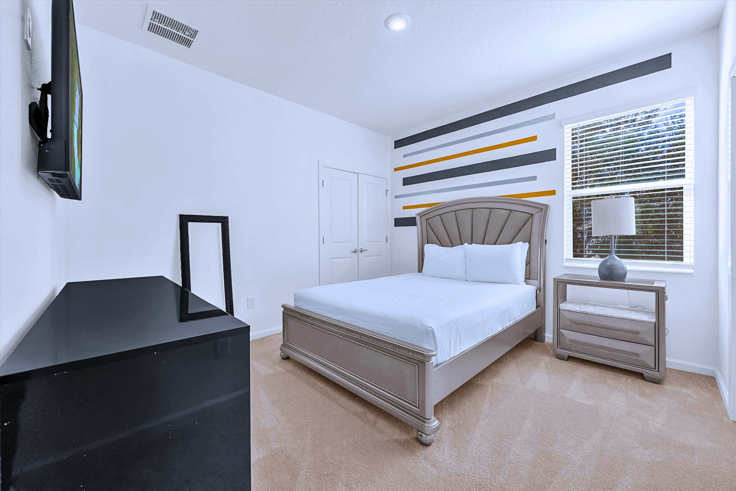 Queen Bed setup featuring plush bedding, headboard, bedside lamp & floor mirror
