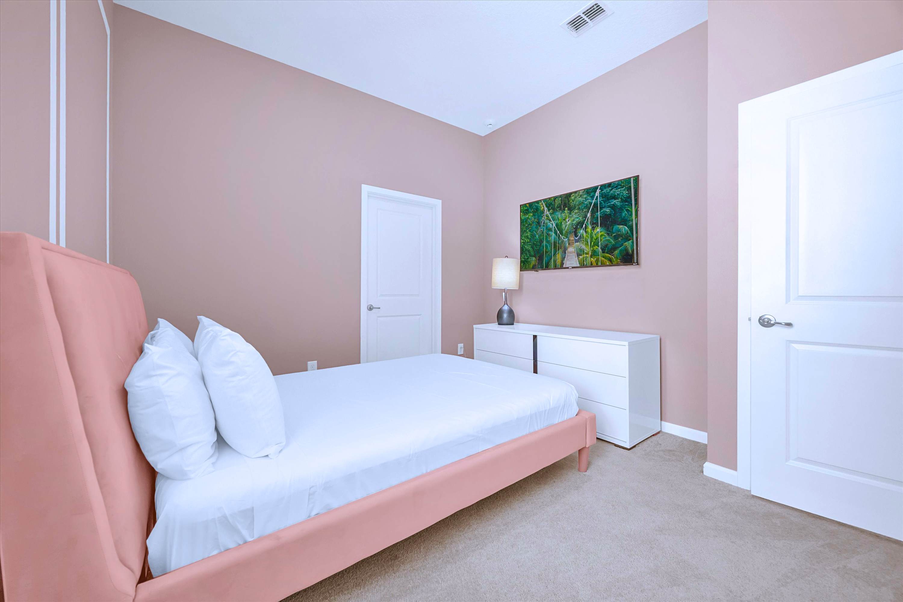 Stylish pink Queen Bed setup featuring custom headboard, luxury bedding, TV & lamp