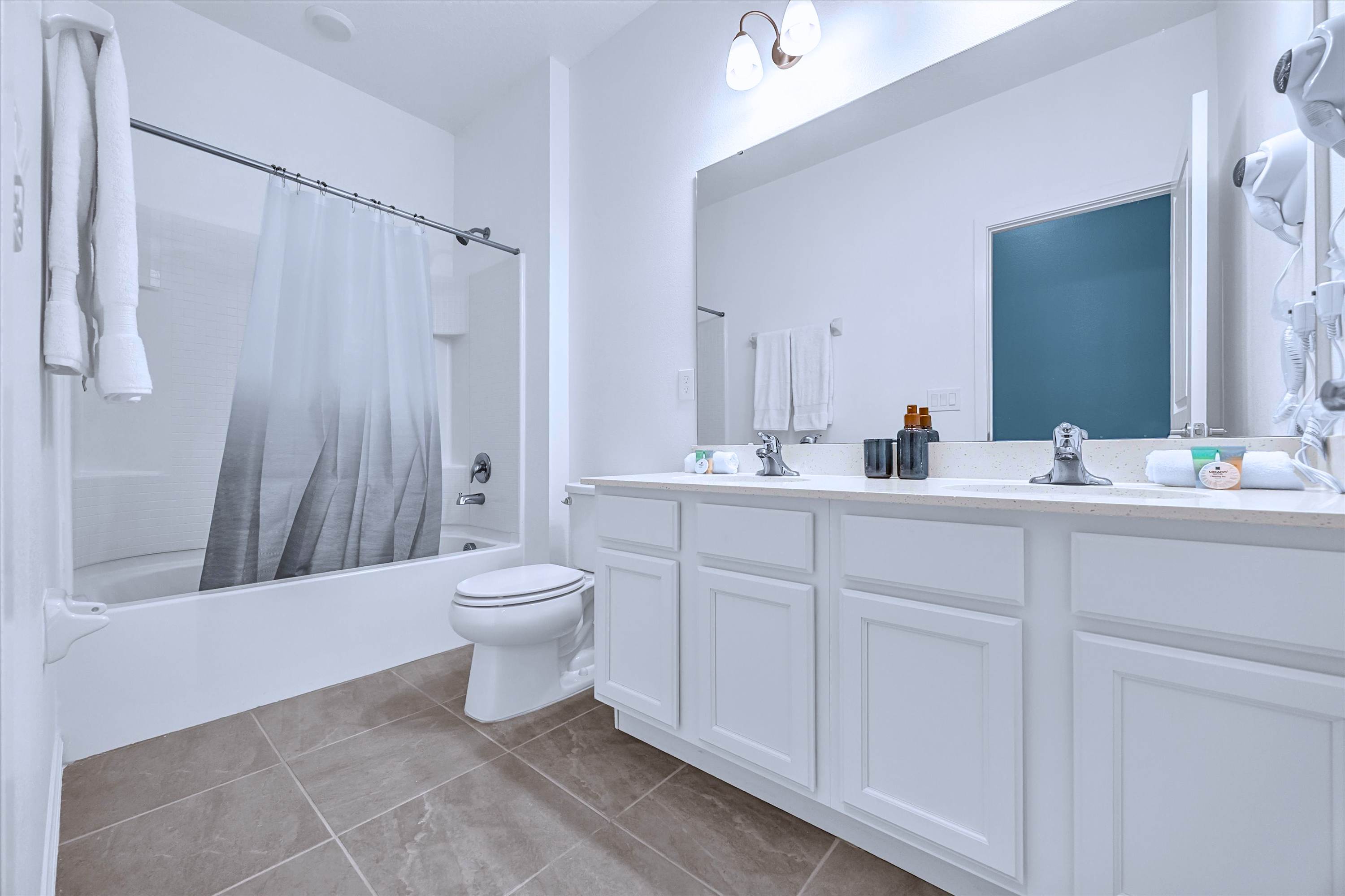 En-suite full bathroom featuring a bathtub shower combo, sink vanity, mirror & toilet