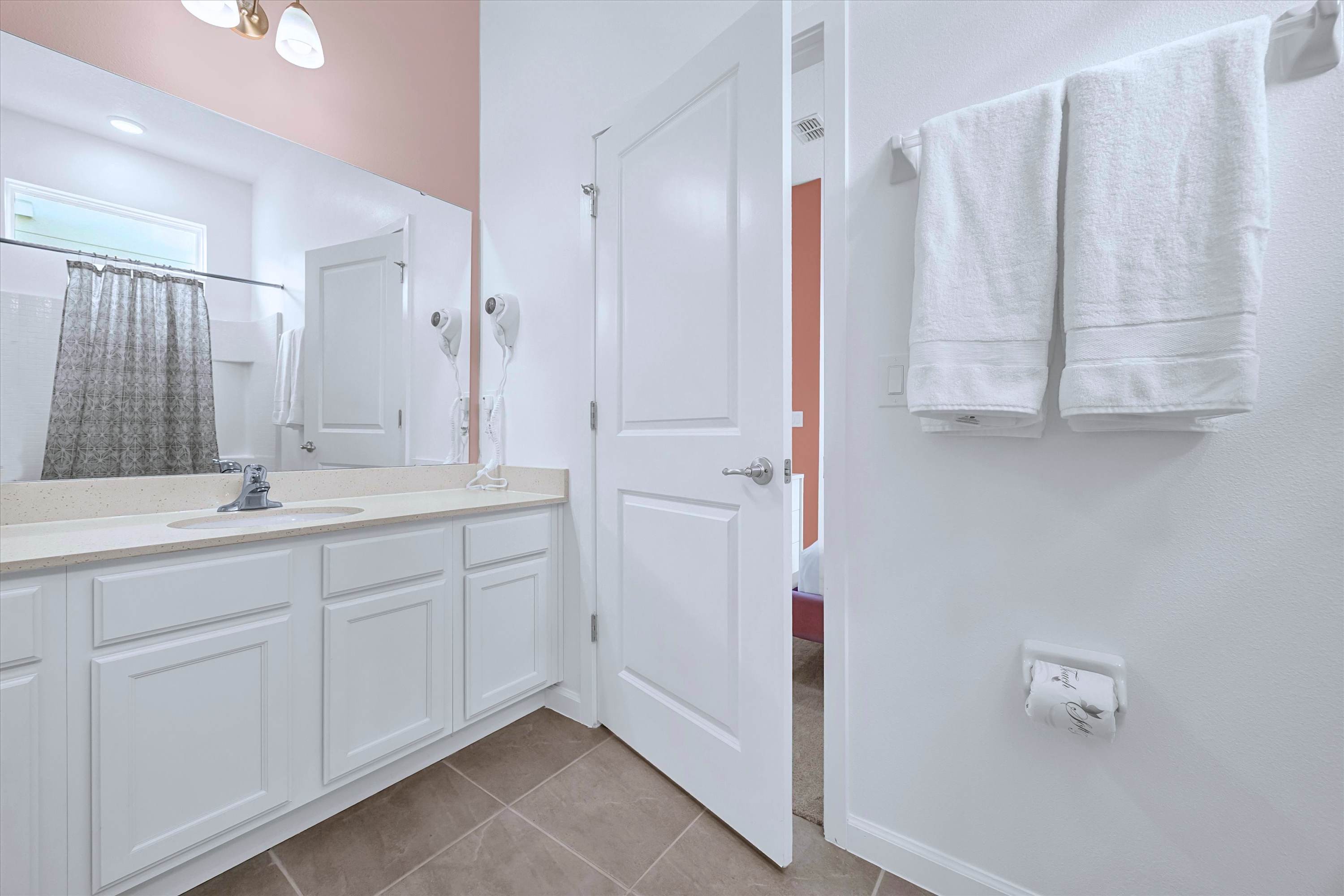 Clean en-suite bath setup featuring modern sink vanity and full-width mirror