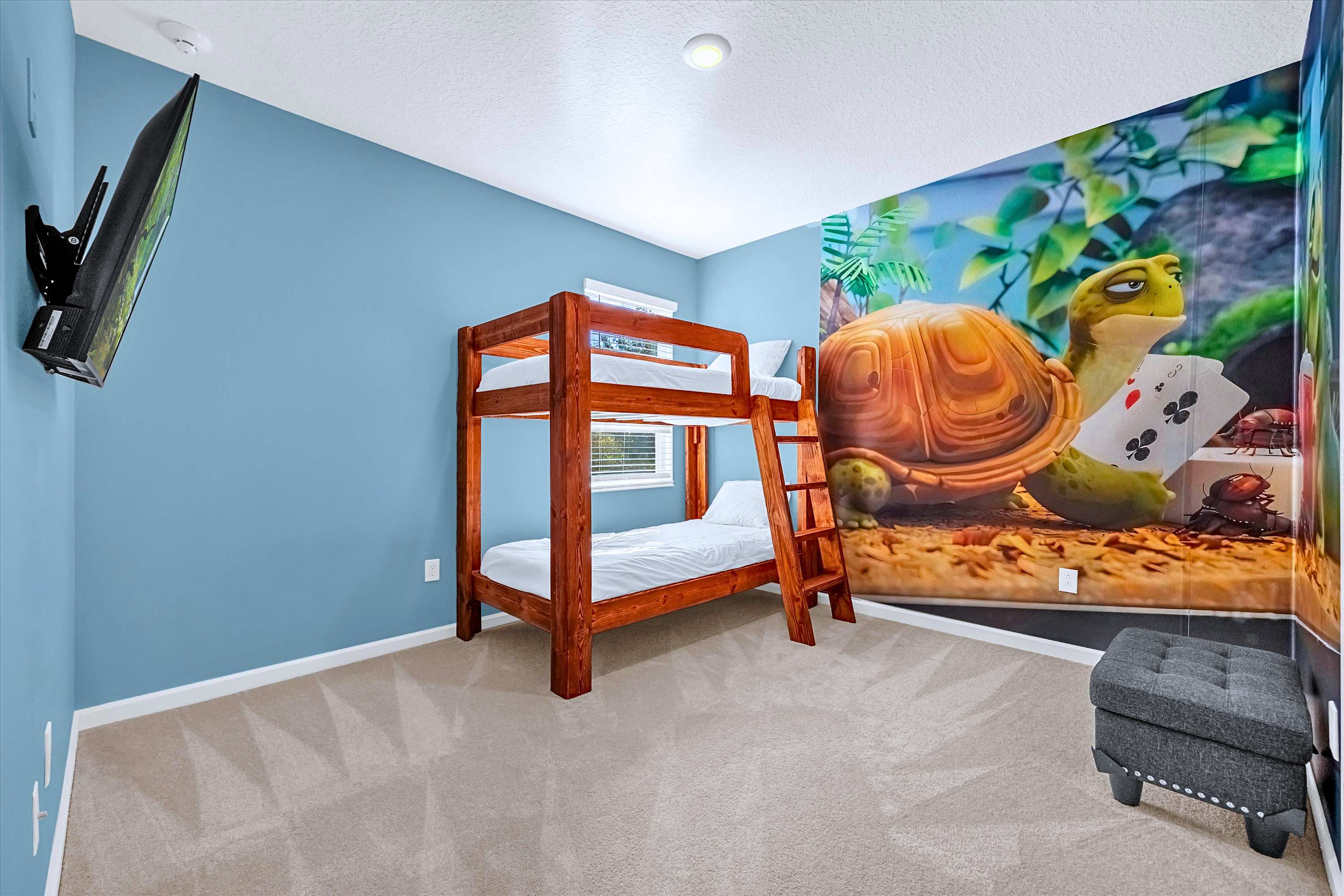Playful cartoon-themed bedroom with bunk bed, wall-mounted TV & character art.