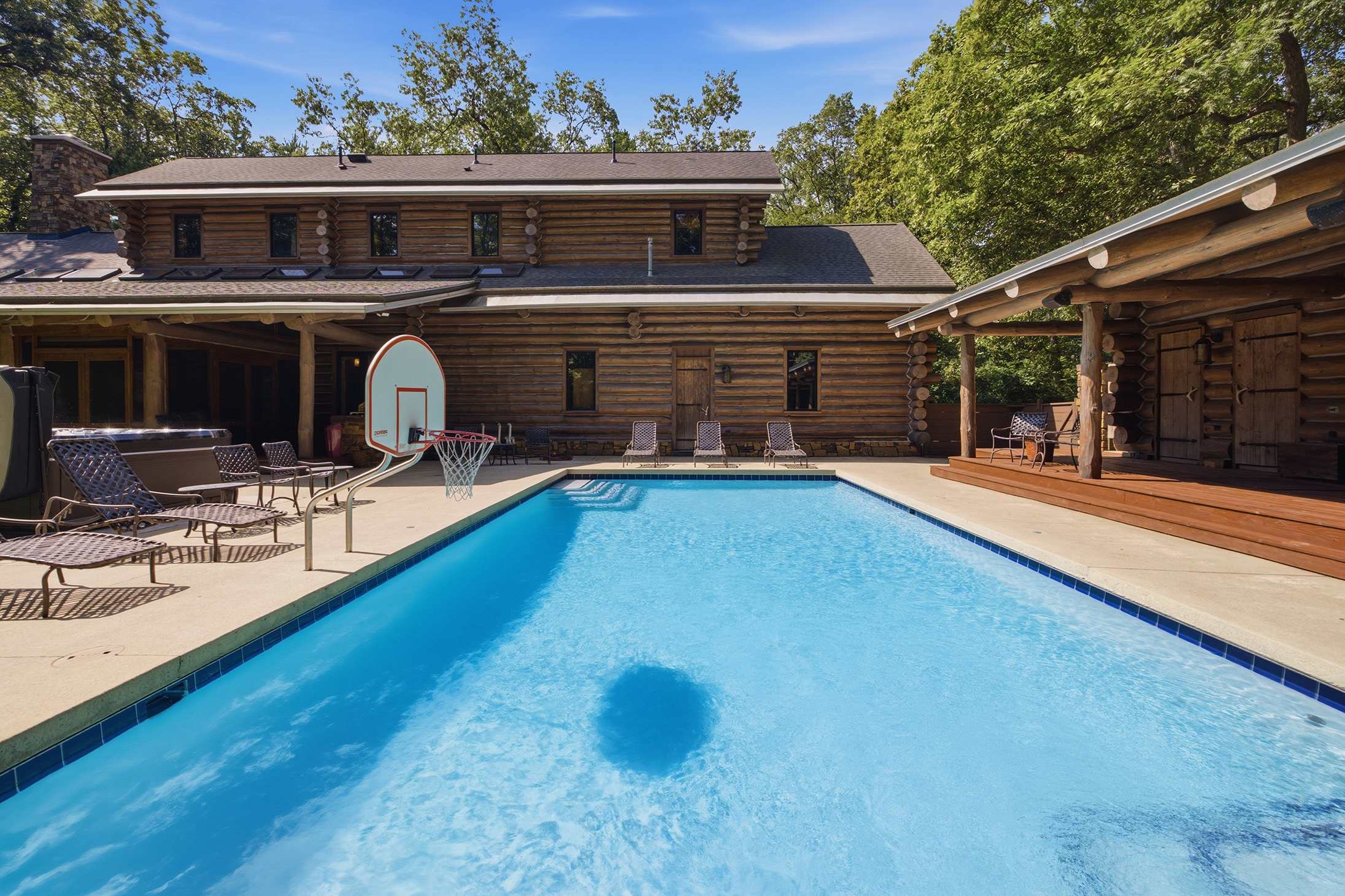 A private log estate with pool, hot tub, and covered lounging in nature.