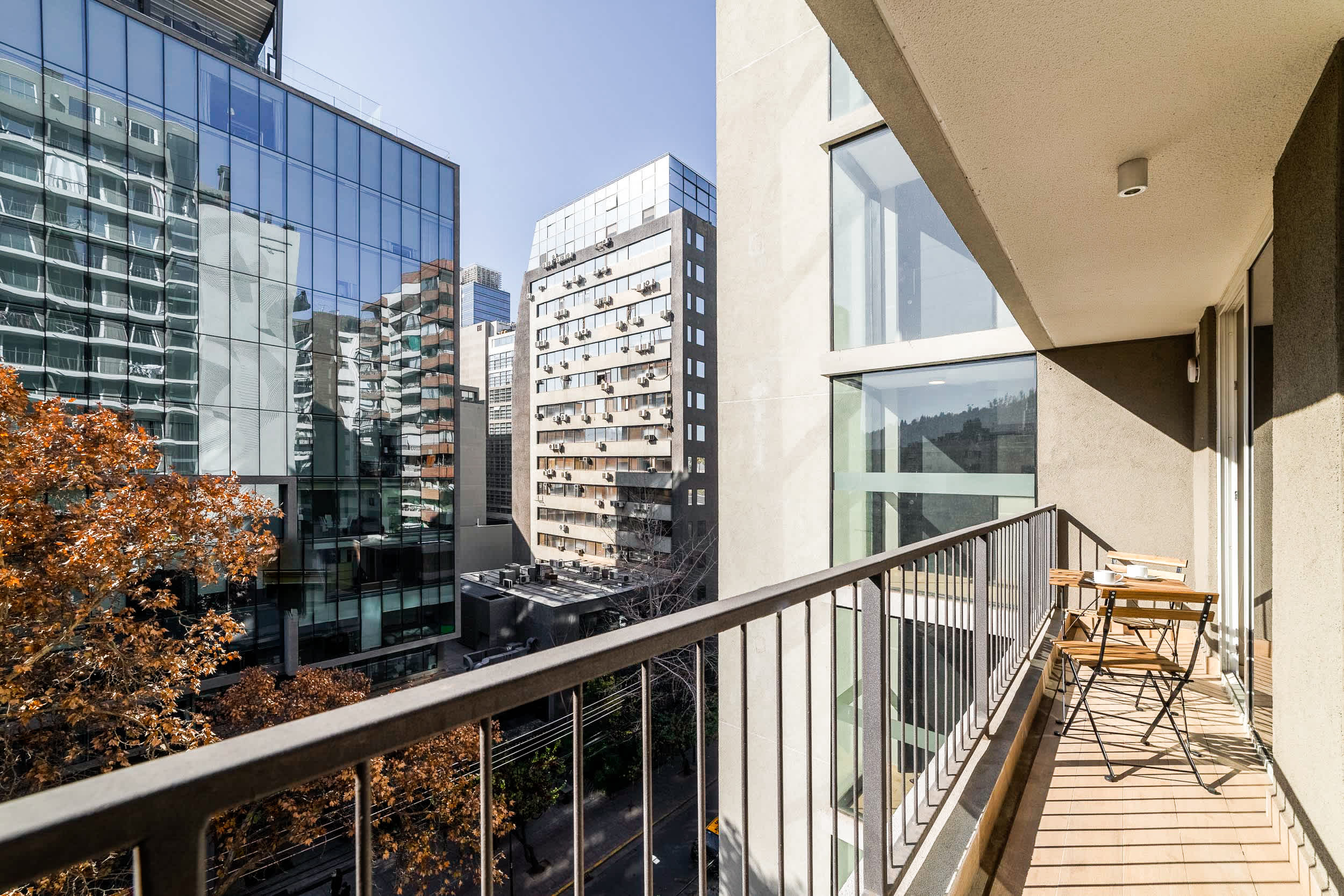 Private balcony with café seating and expansive views across Santiago’s modern city skyline.