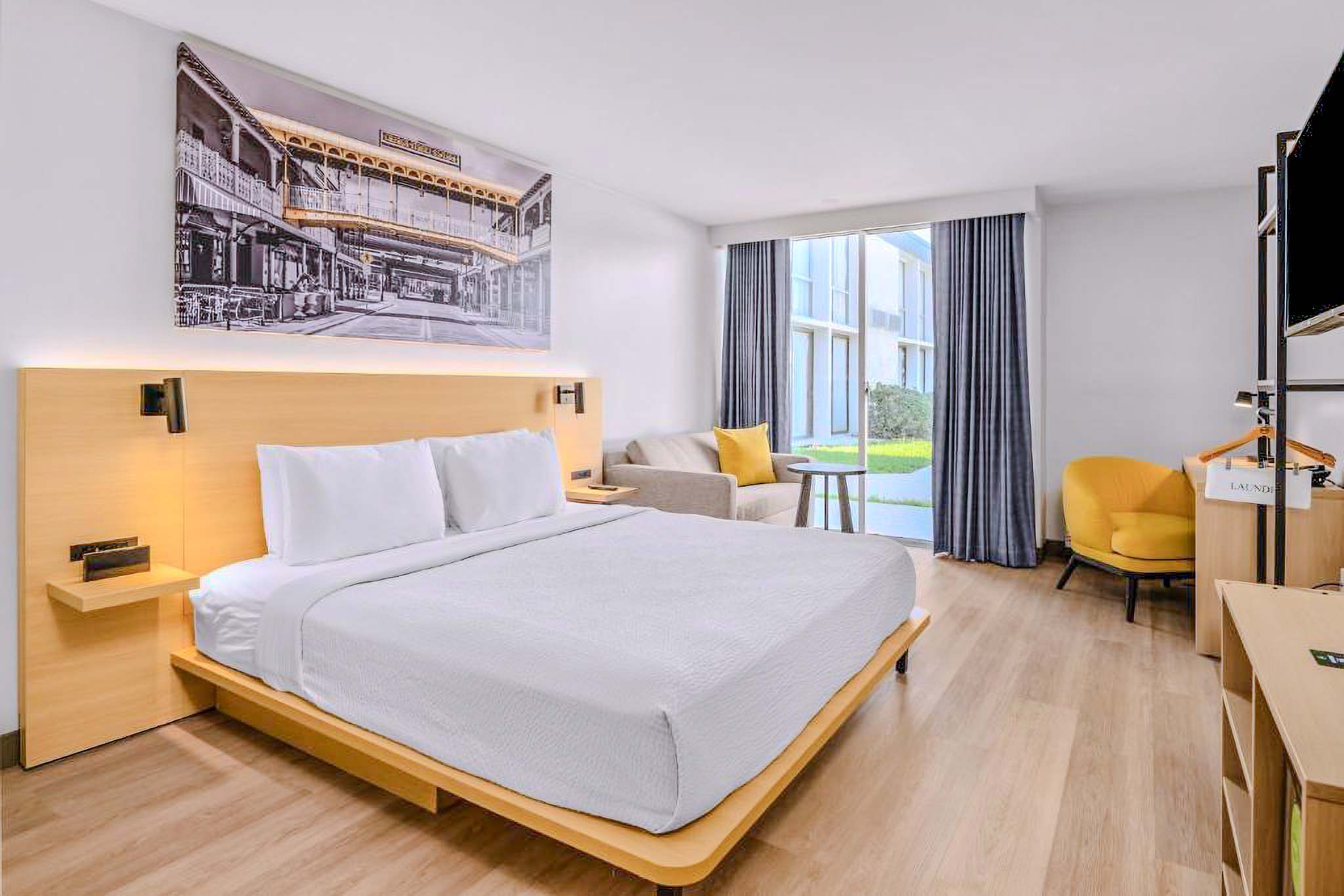 A hotel room with a large bed, desk, chair, and window