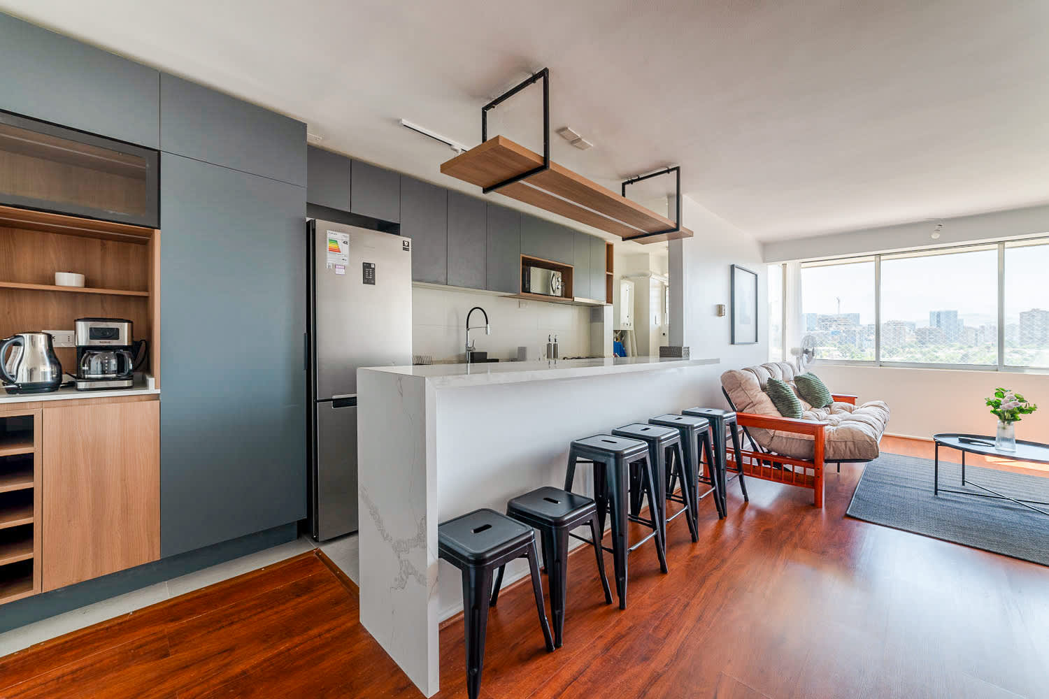 Private kitchen with a waterfall island, five bar stools, and large windows overlooking the city skyline.