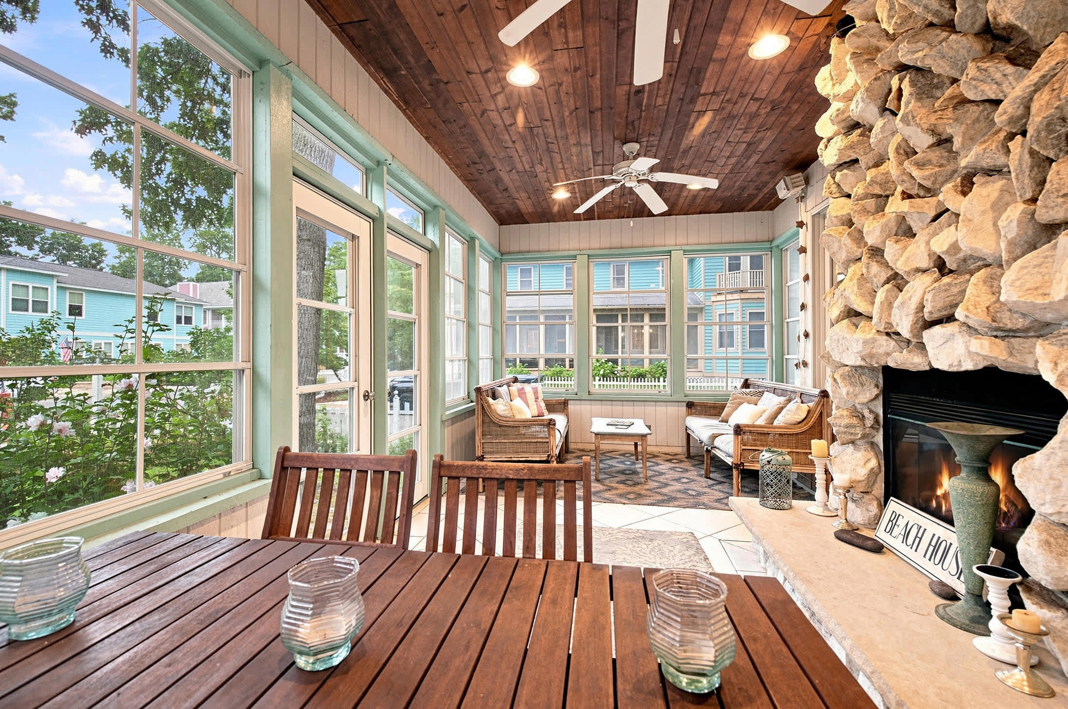 Four-season room with dining and lounge seating gathered around the fireplace.