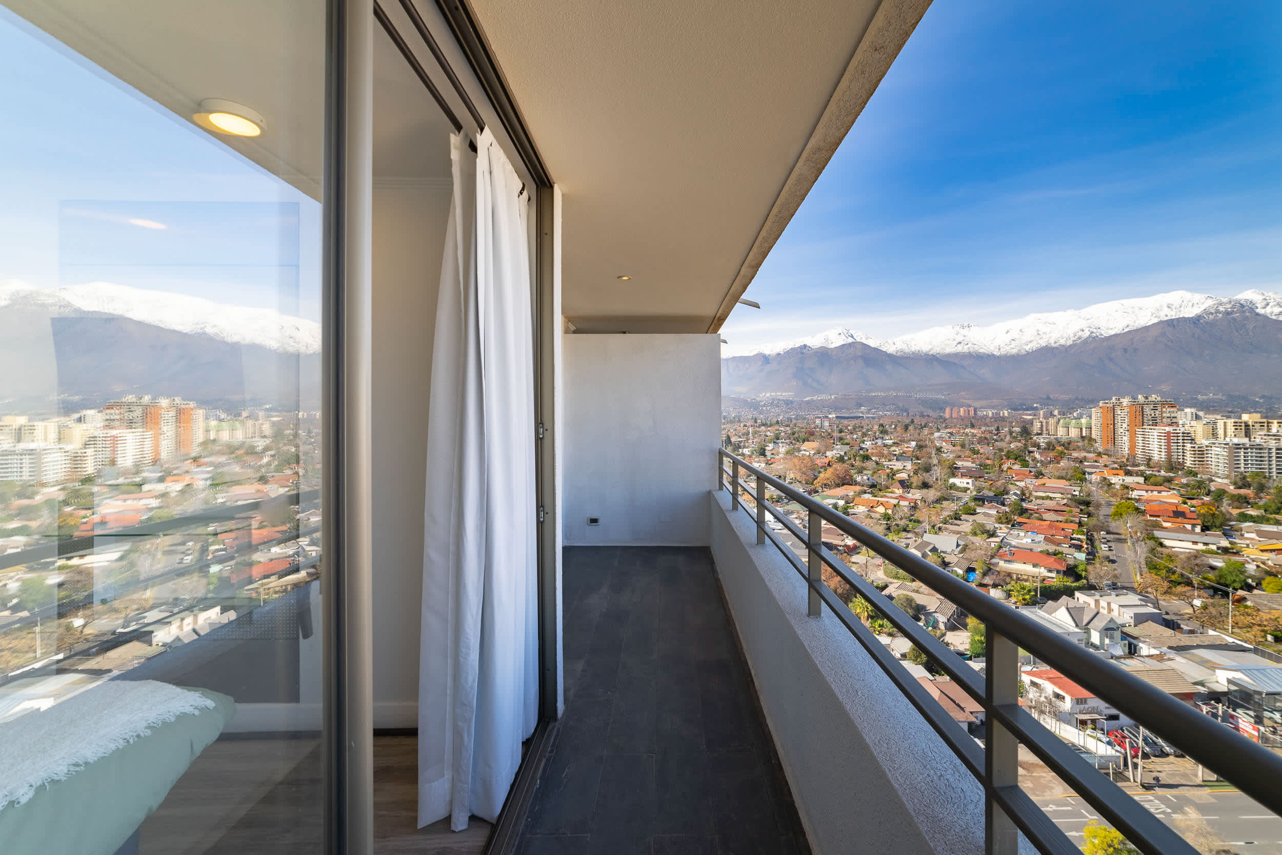 Private balcony with sweeping views of Santiago, city rooftops, and the snow-capped Andes.
