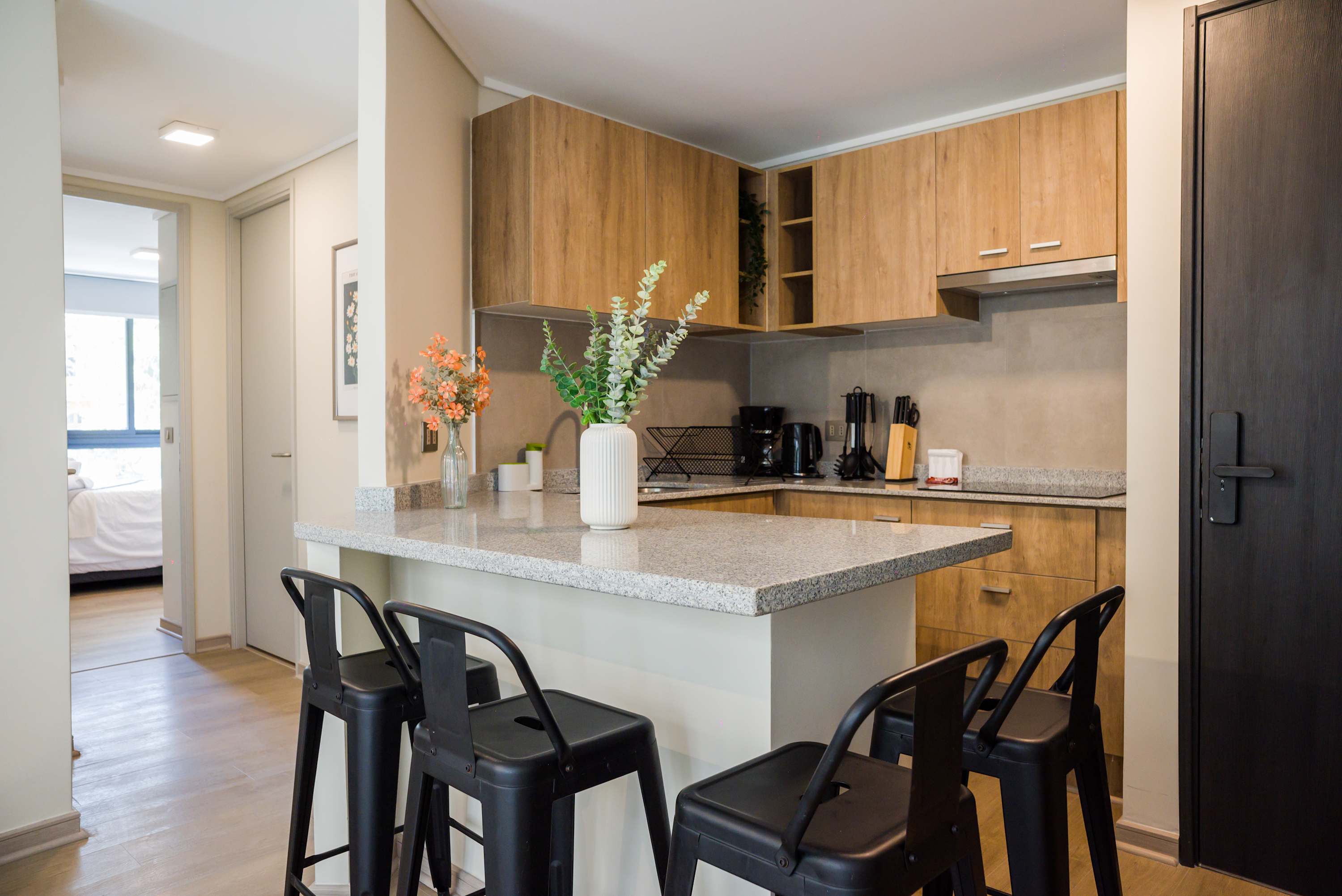 Private kitchen with warm wood cabinetry, a stone island, coffee station, and seating for five.