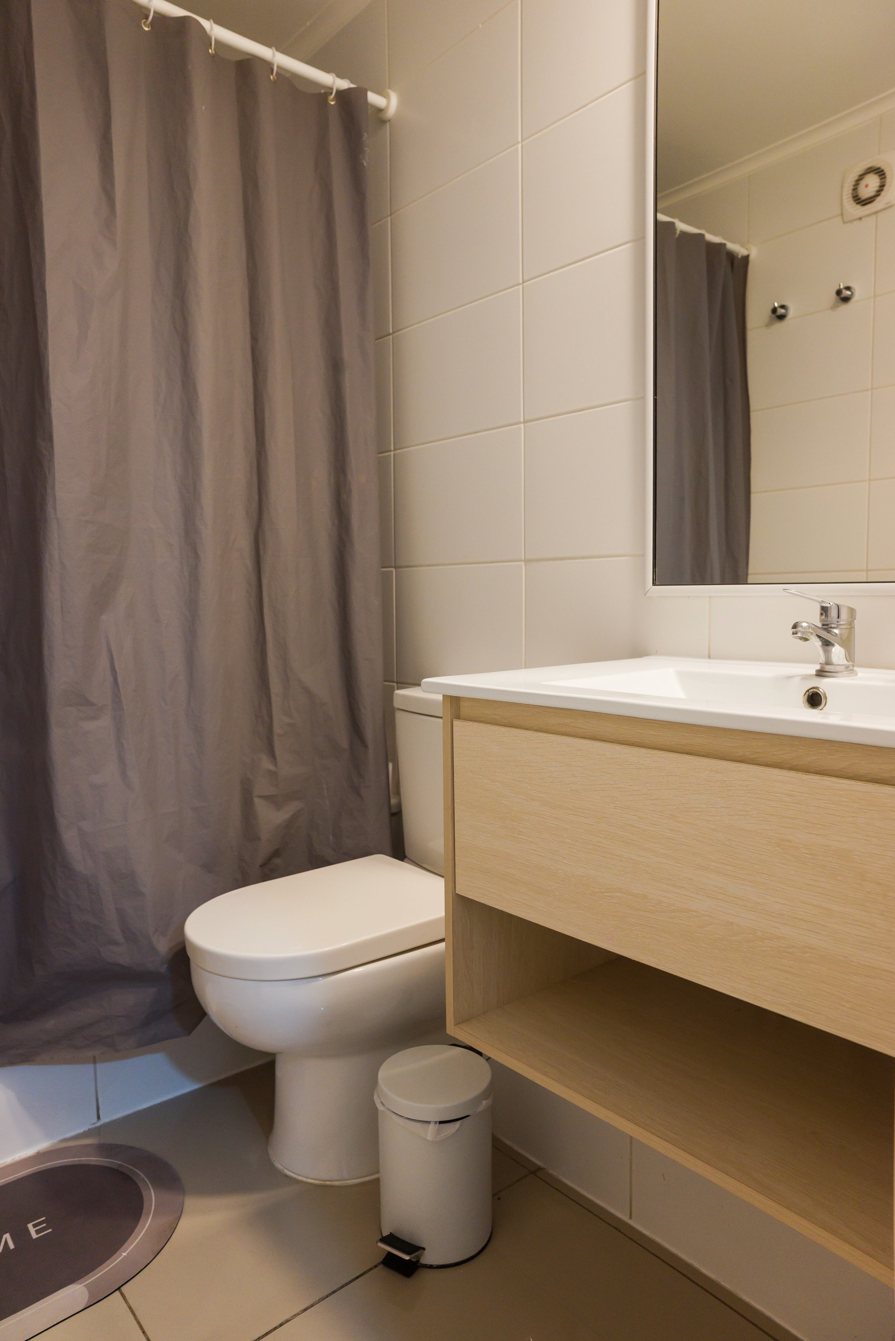 Private bathroom with a light wood vanity, mirrored cabinet, and enclosed shower.