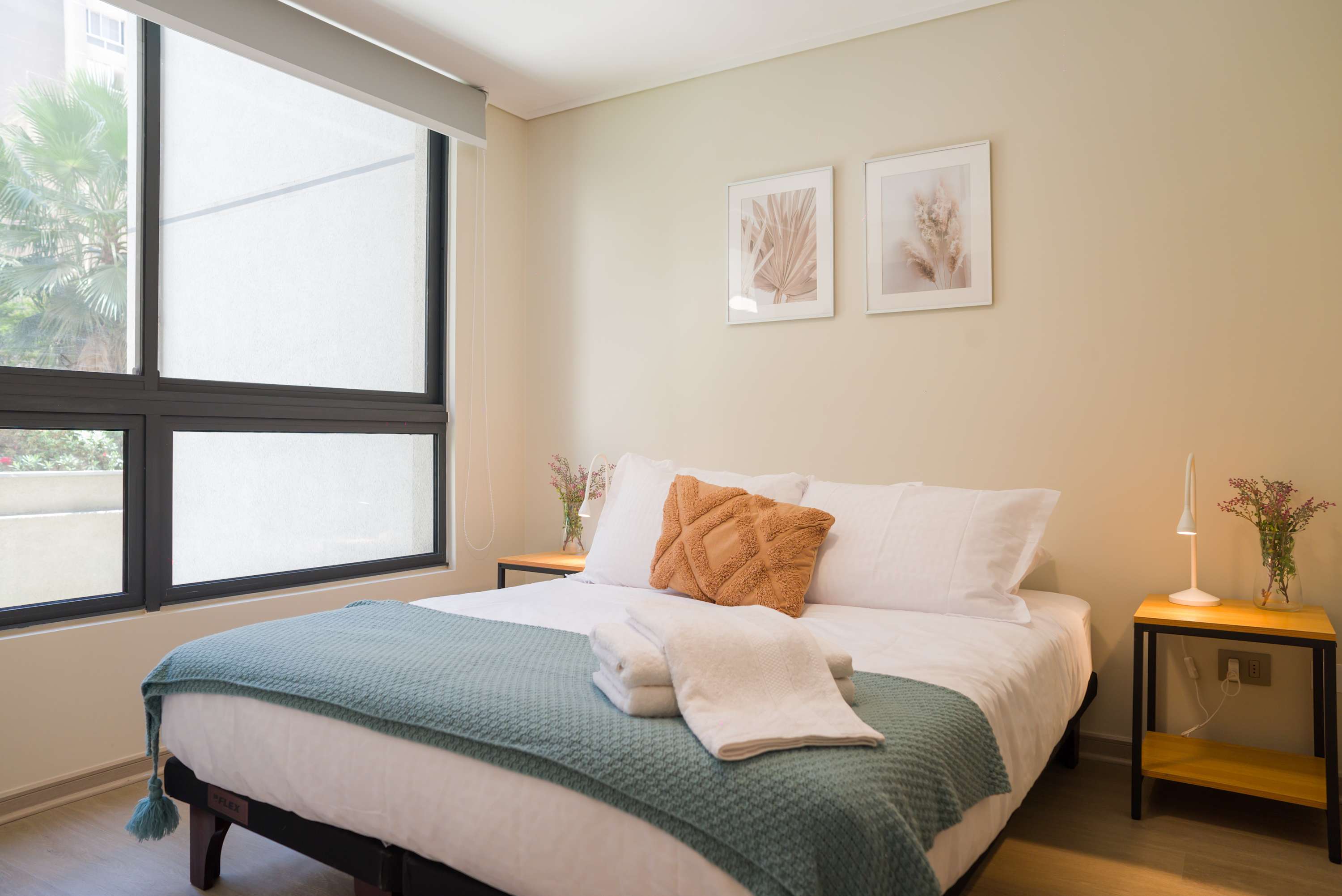Private bedroom with crisp white bedding, a textured blue-green throw, and palm views through the large window.