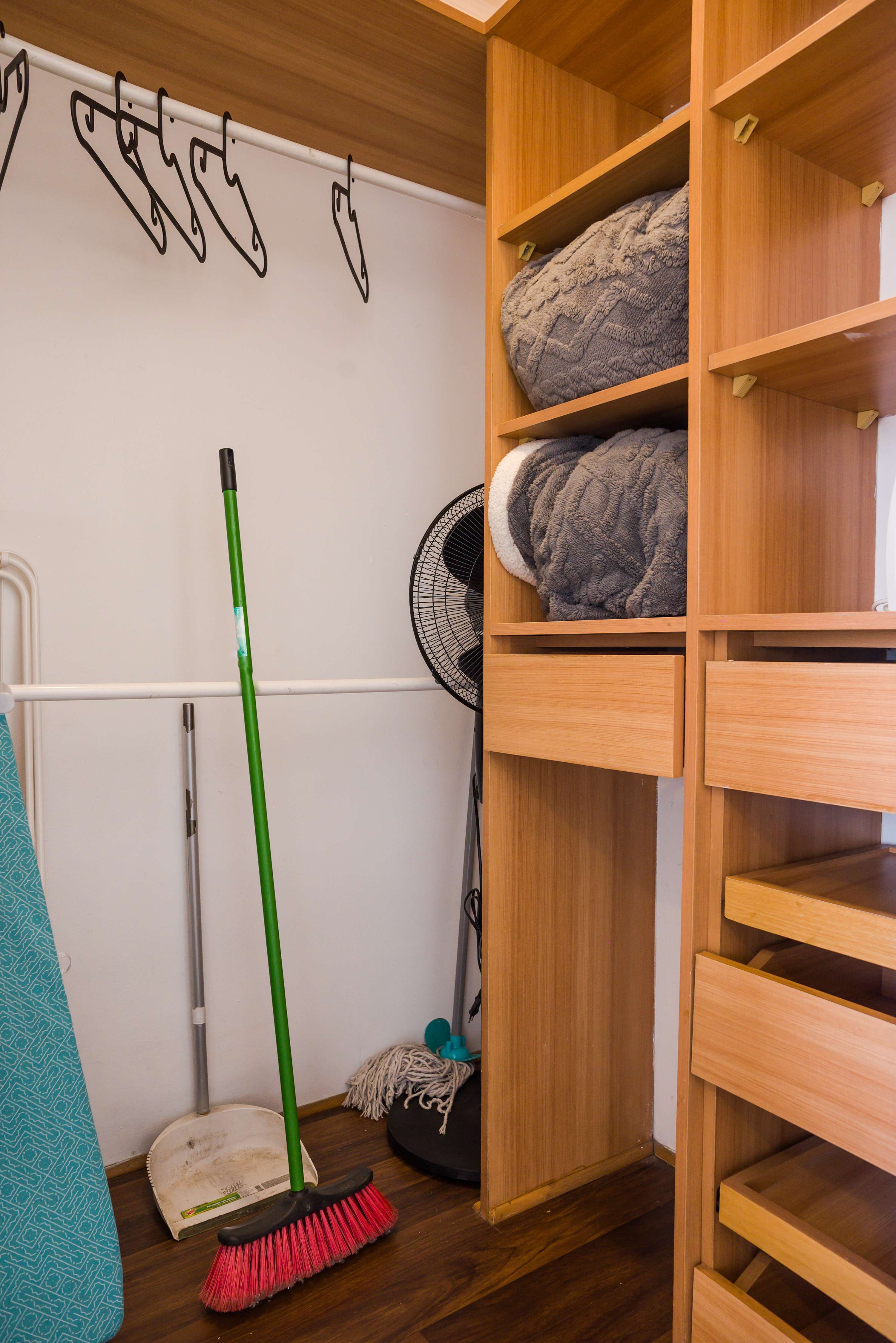 Utility storage area with built-in wood shelving and extra folded blankets.