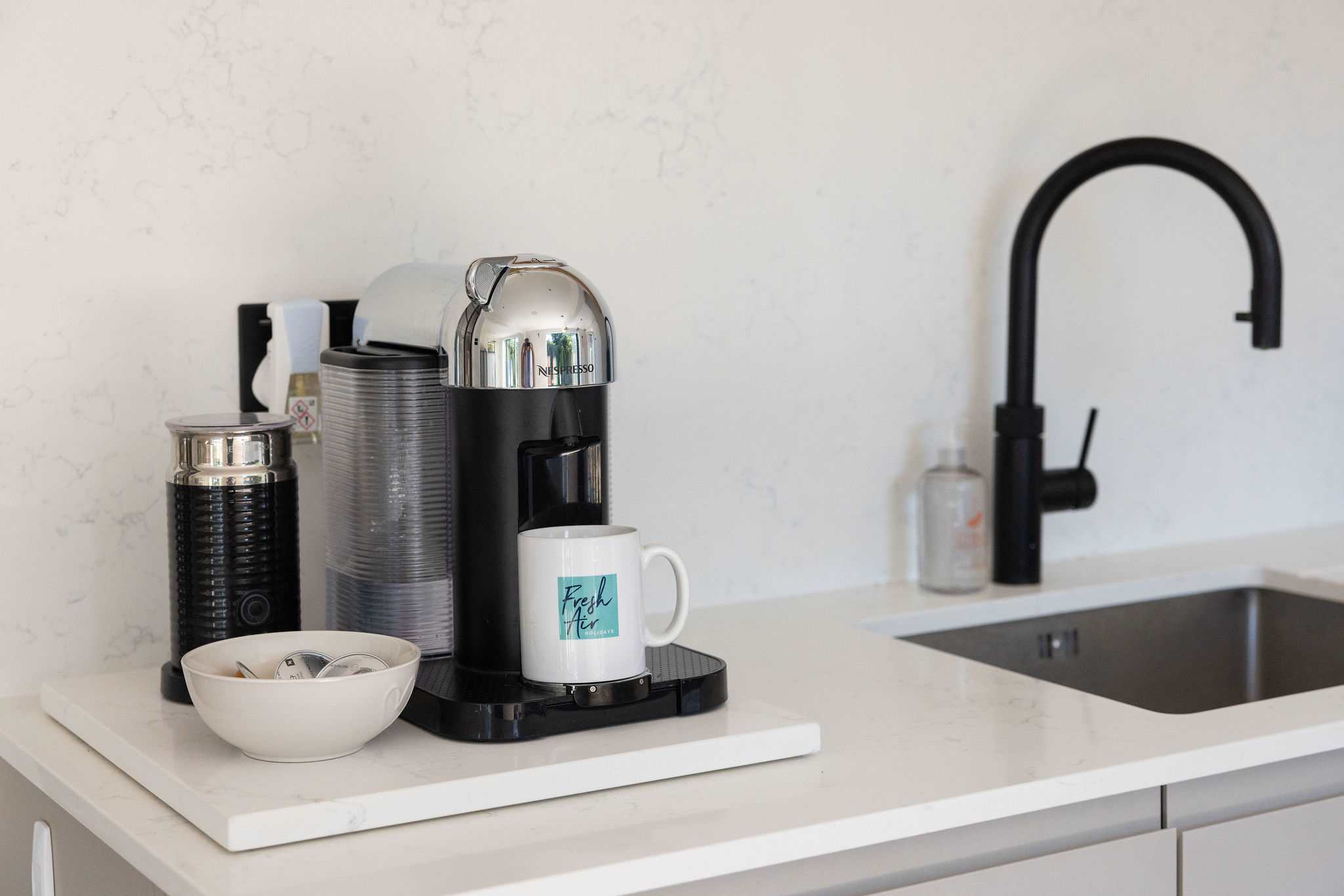 A sleek coffee station with a stylish pod machine, crisp worktops and elegant finishes — a polished little corner for slow mornings and freshly brewed coffee.