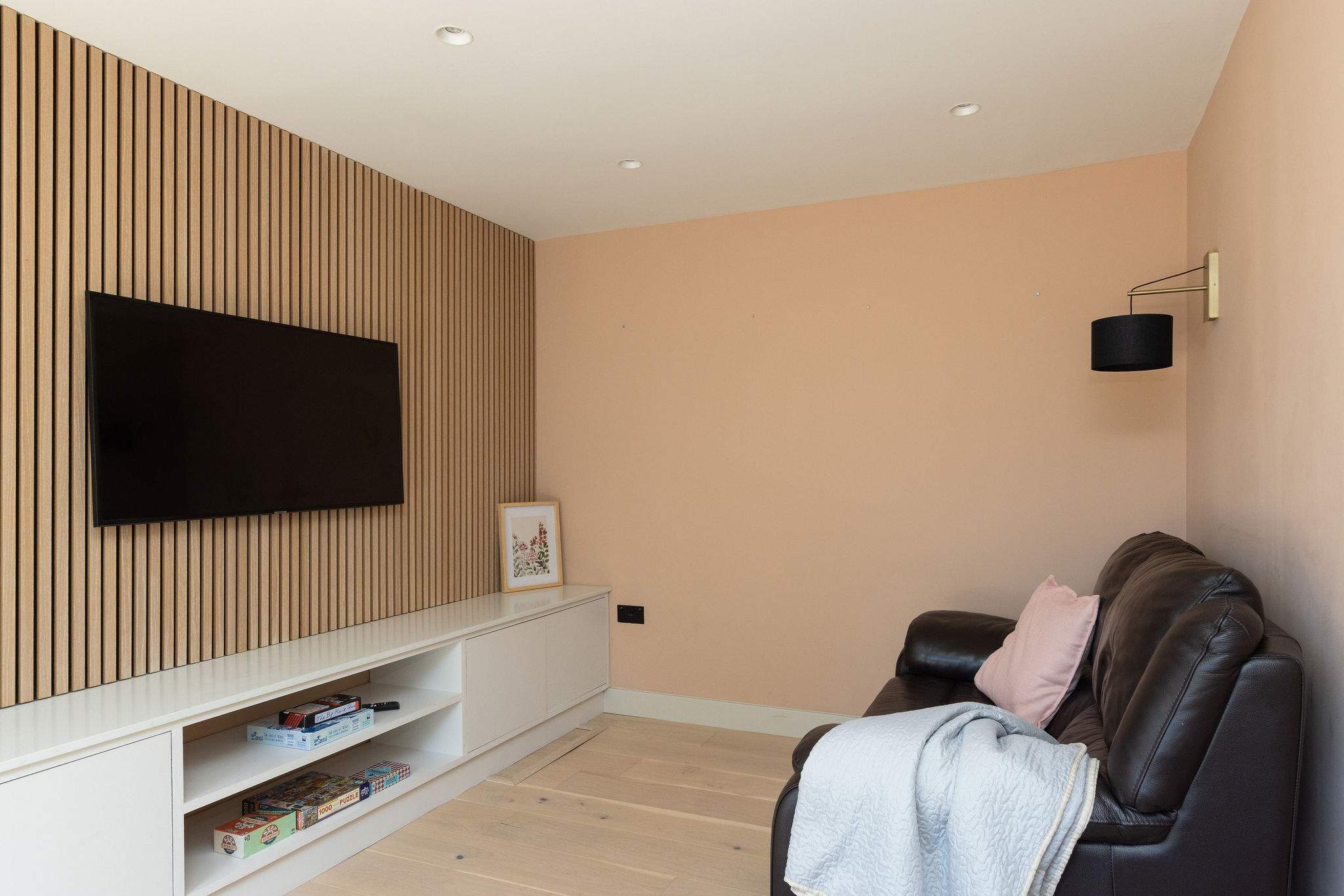 A cosy snug room with a comfy sofa and TV, offering a quieter space to relax, with doors opening directly out to the garden.