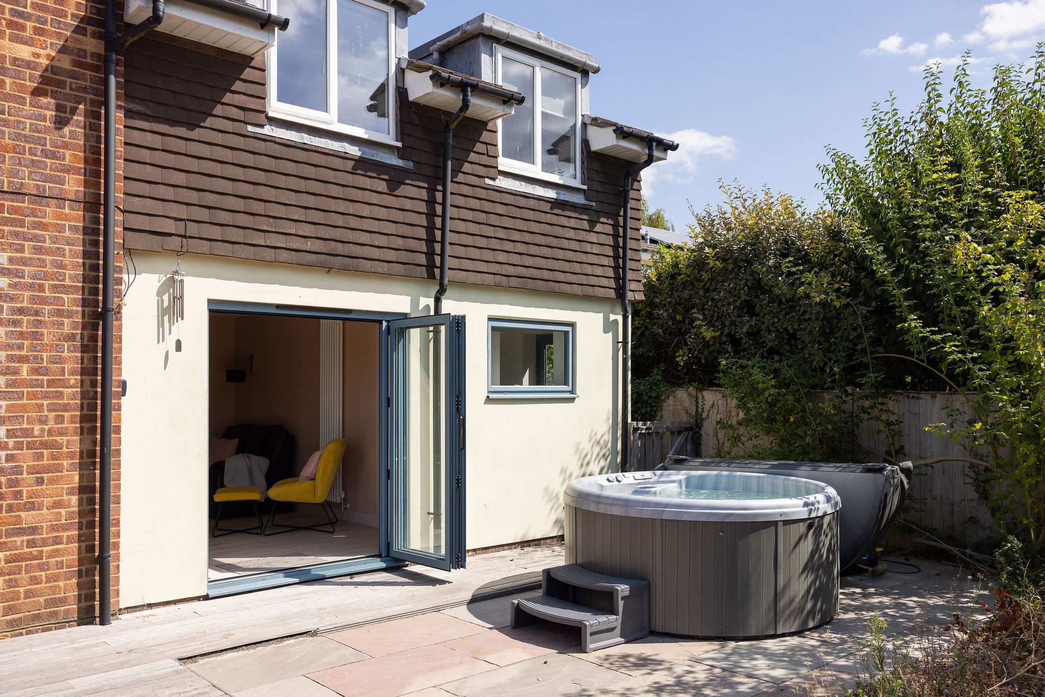 Private hot tub set on the sunny rear patio, with direct access into the house and a peaceful, enclosed garden setting for relaxed outdoor living.