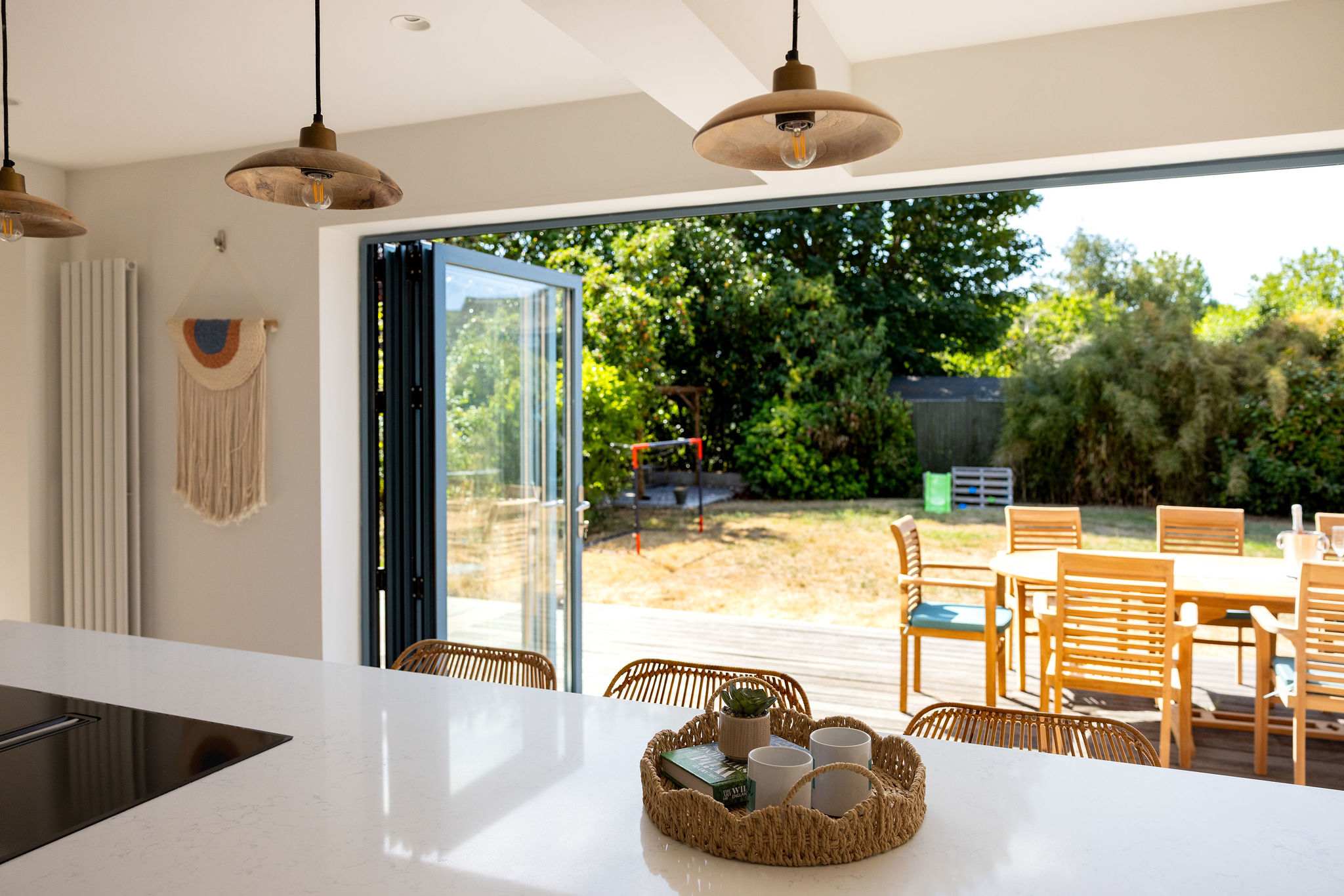Light-filled kitchen with wide bi-fold doors opening straight onto the outdoor dining terrace and garden, creating a beautiful sense of space and effortless indoor-outdoor living.