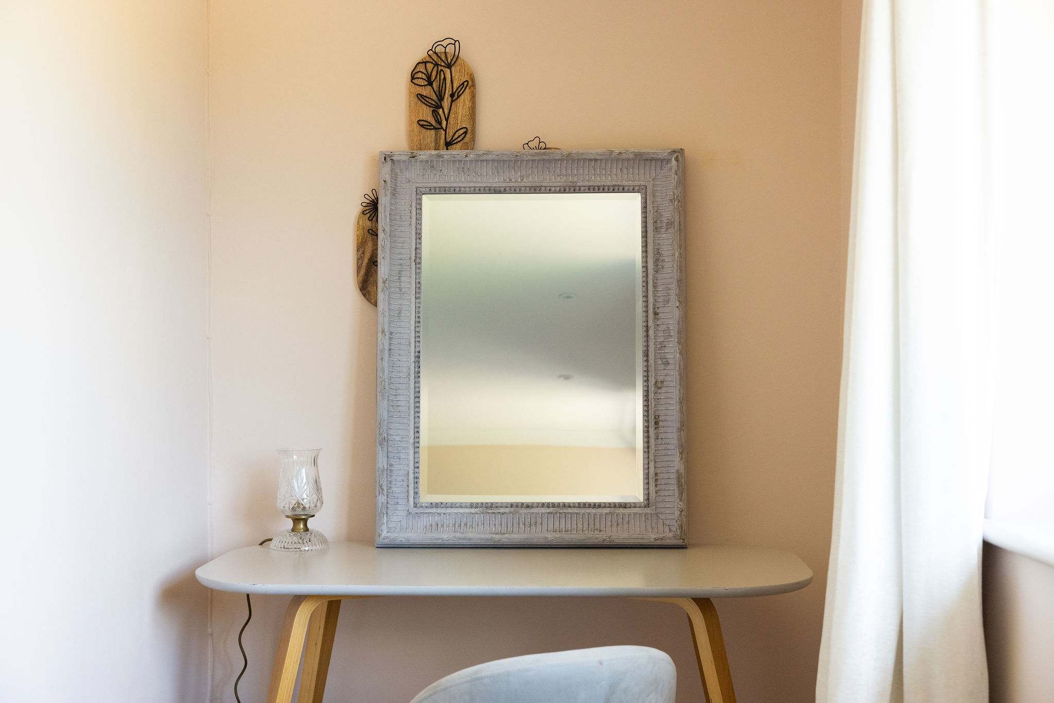 A dedicated dressing area with a statement mirror, slim console and comfortable chair — a lovely little spot to get ready for the day.