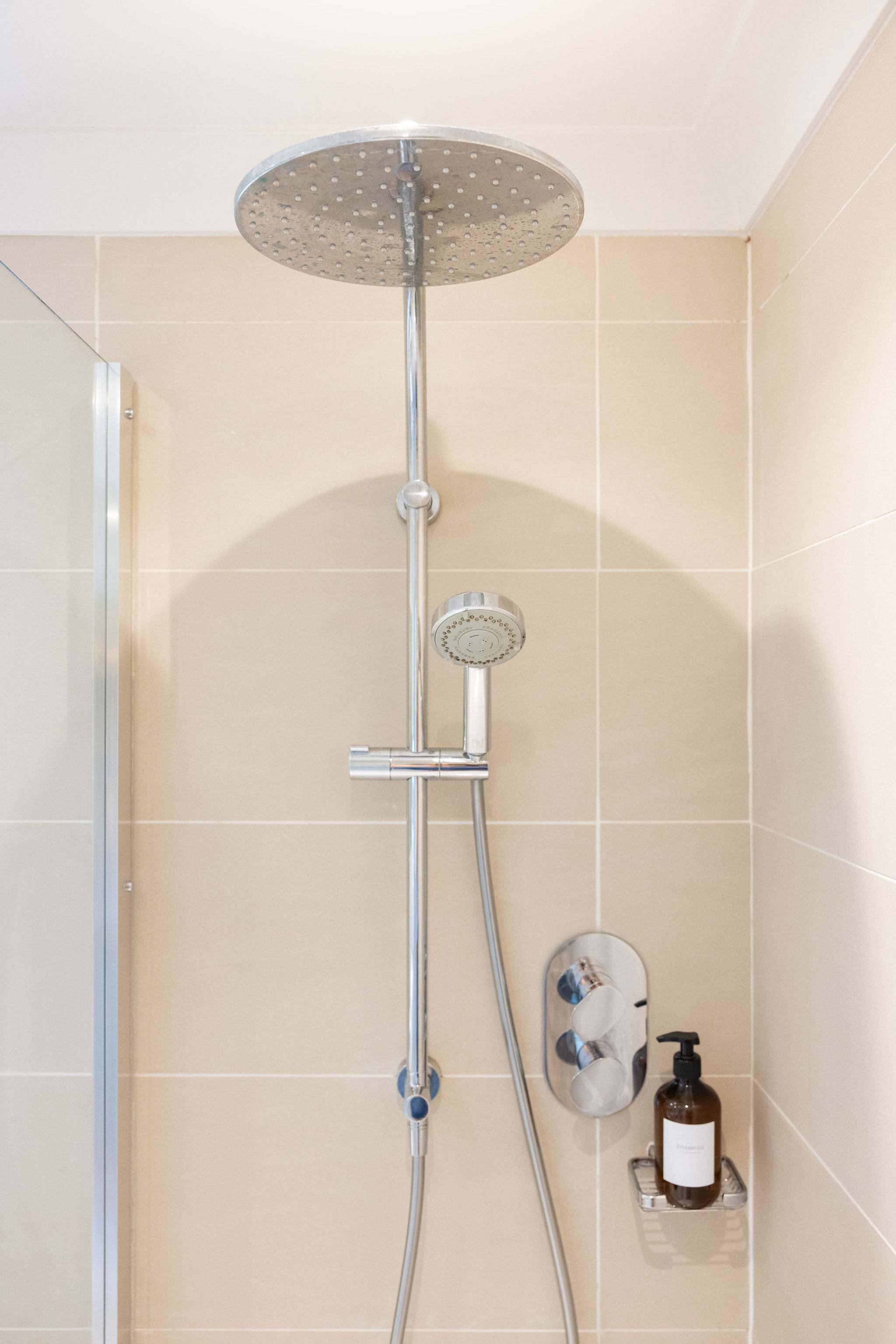 Contemporary shower with an overhead shower head, separate handheld attachment and sleek chrome fittings.